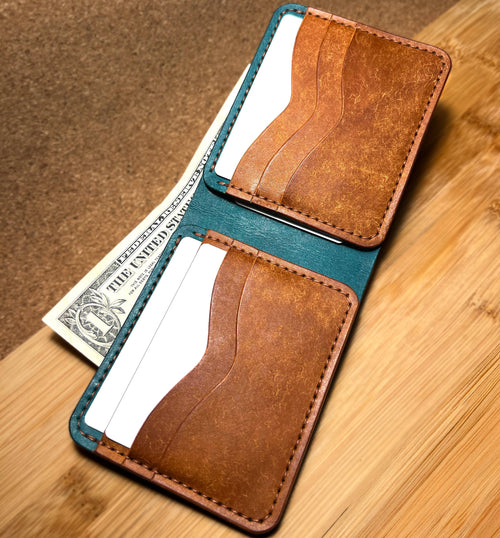 Brown leather wallet with teal interior on a wooden surface