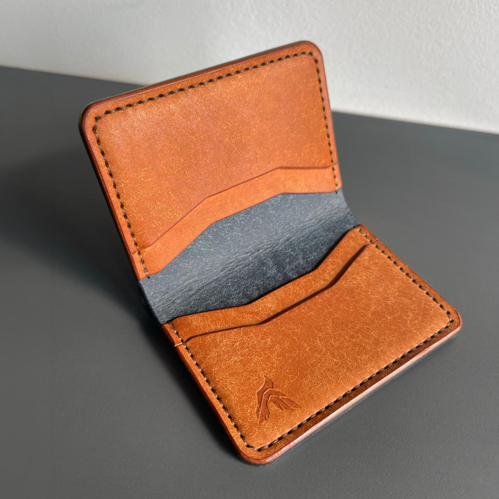 Brown leather wallet with a gray accent on a gray surface