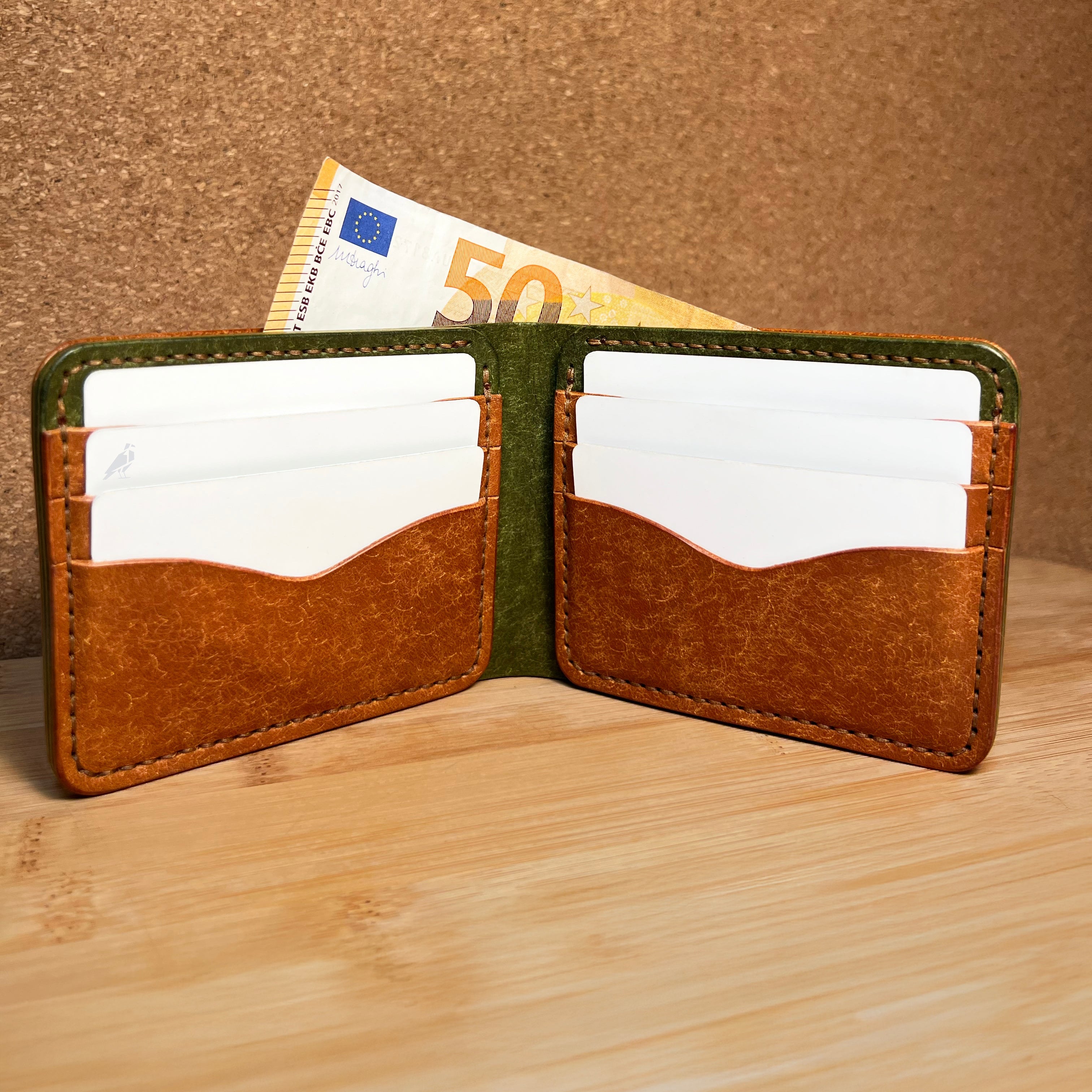 Brown leather wallet with a 50 euro bill on a wooden surface