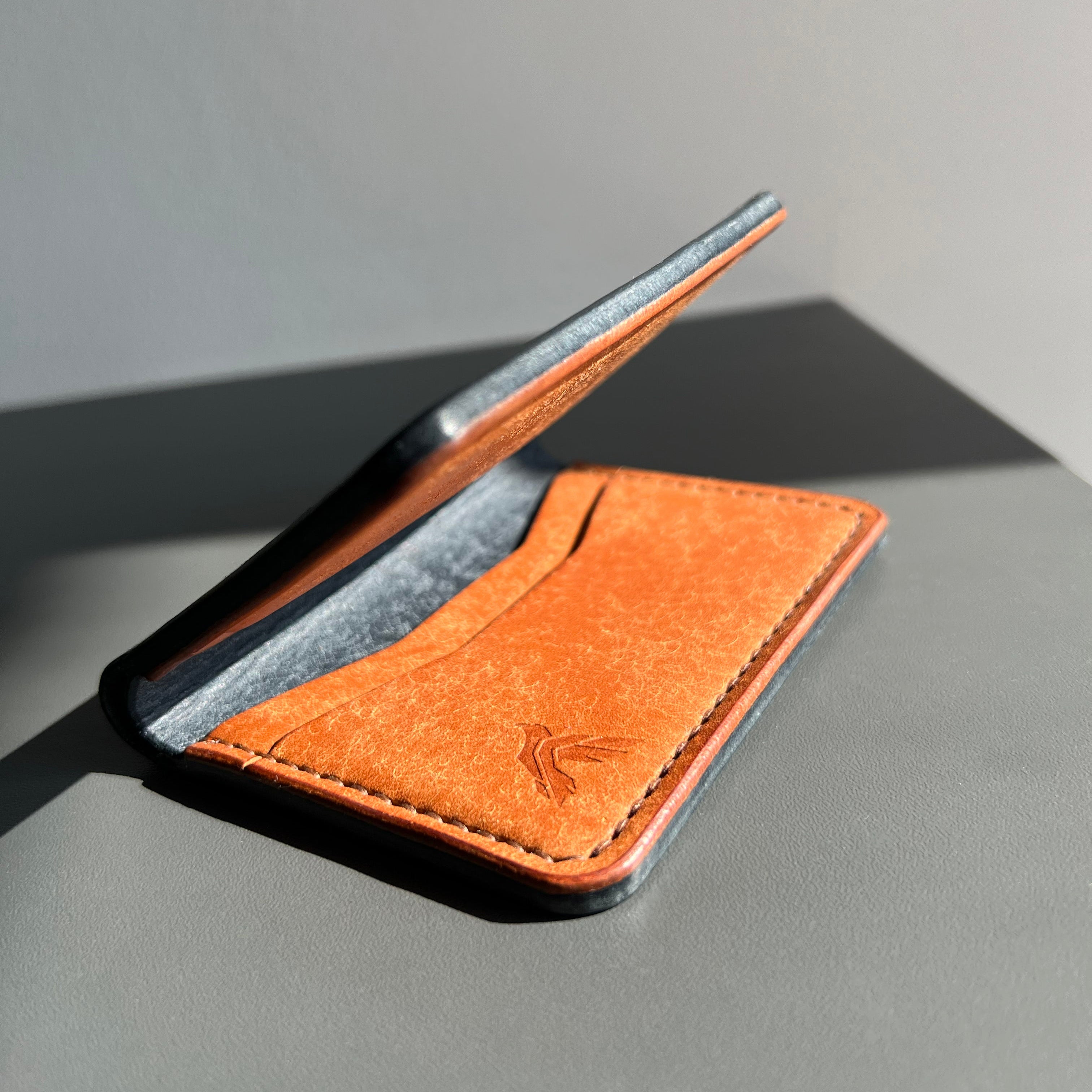 Brown leather cardholder on a gray surface with a neutral background