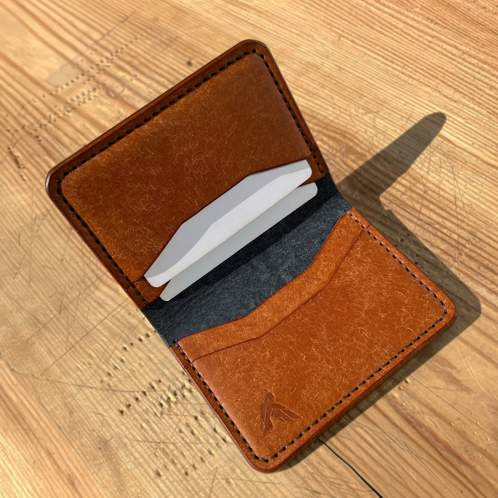 Brown leather wallet with white cards on a wooden surface