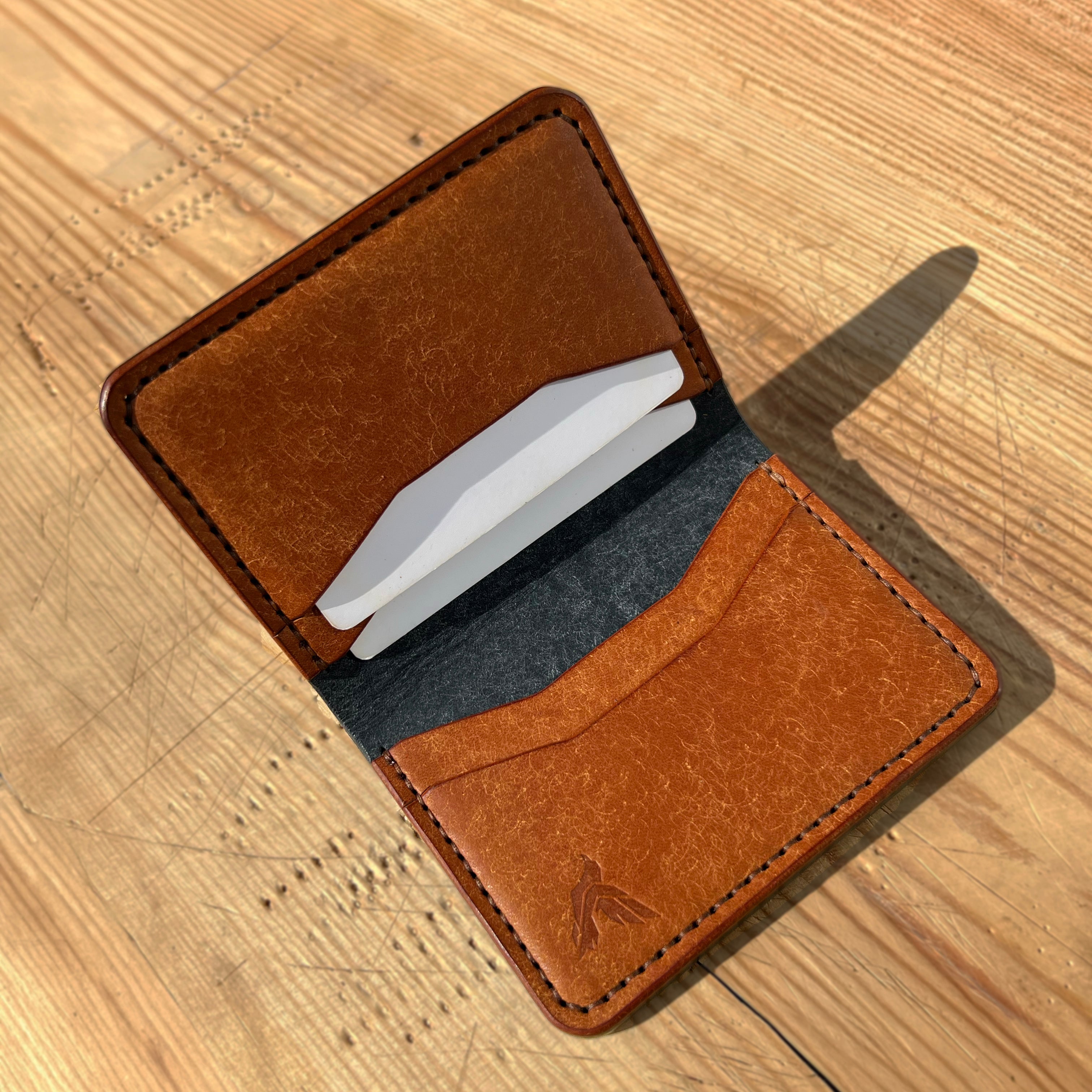 Brown leather wallet with white cards on a wooden surface