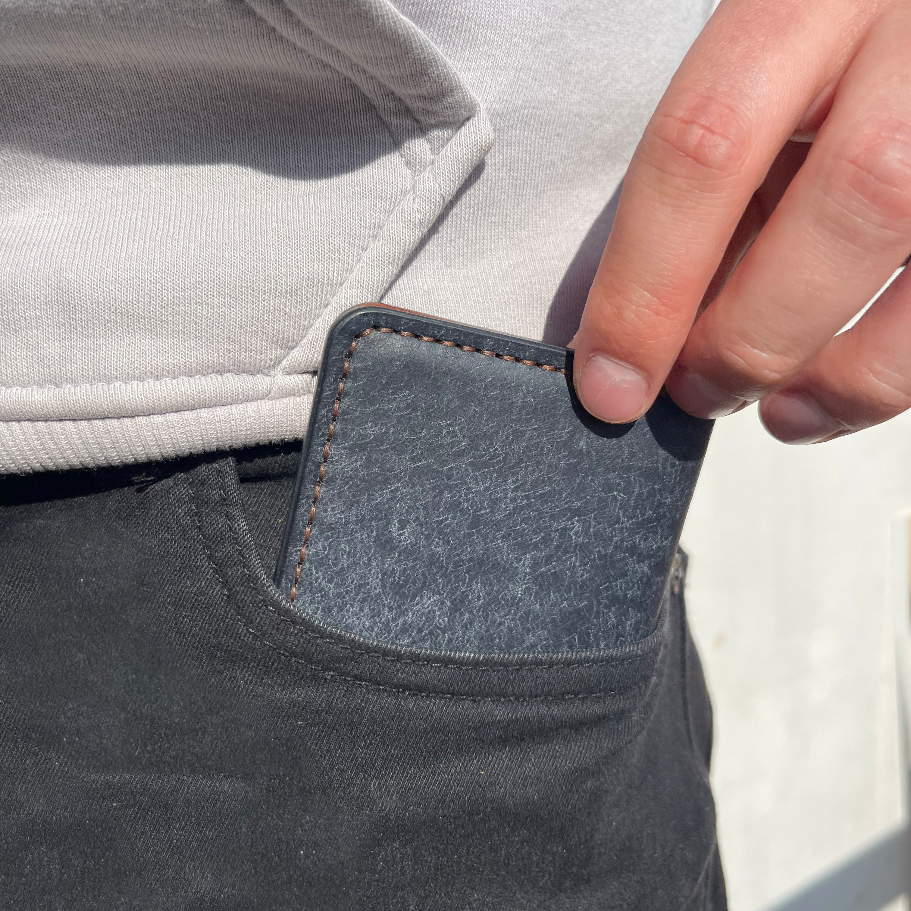 Person wearing a gray hoodie and dark pants with a blue patch on the pocket.
