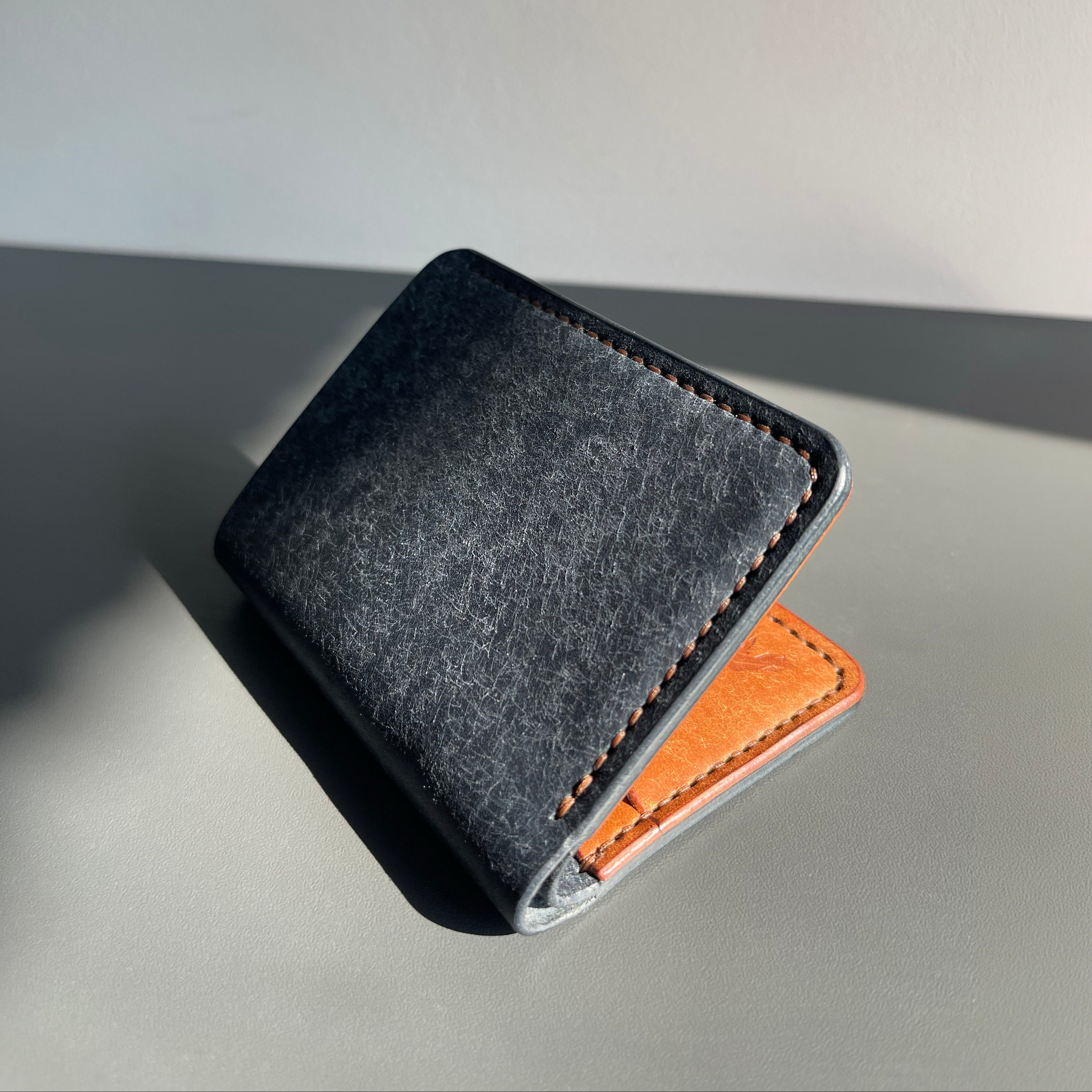 Black leather wallet with brown leather patch on a gray surface