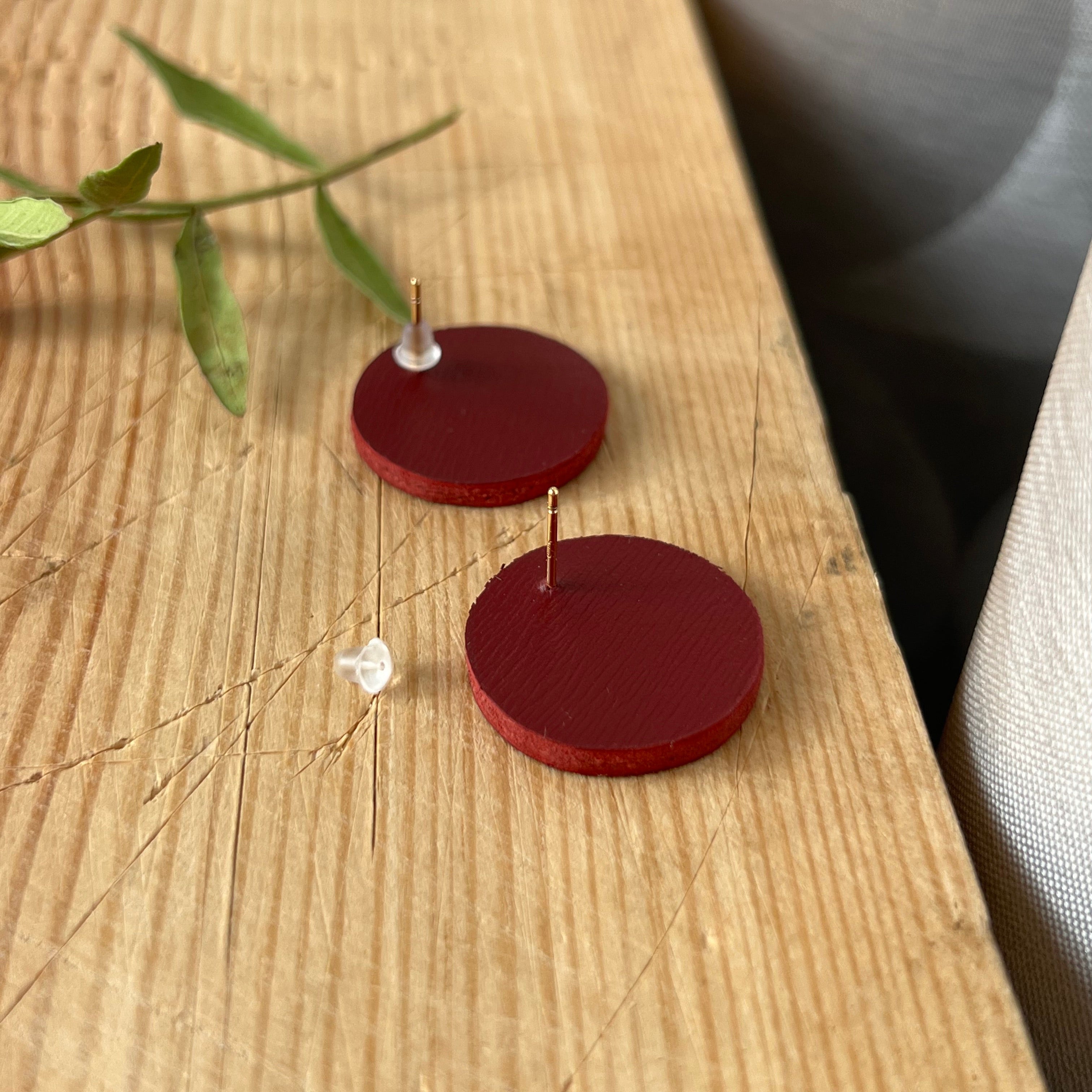 Red circular earrings on a wooden surface with a blurred background