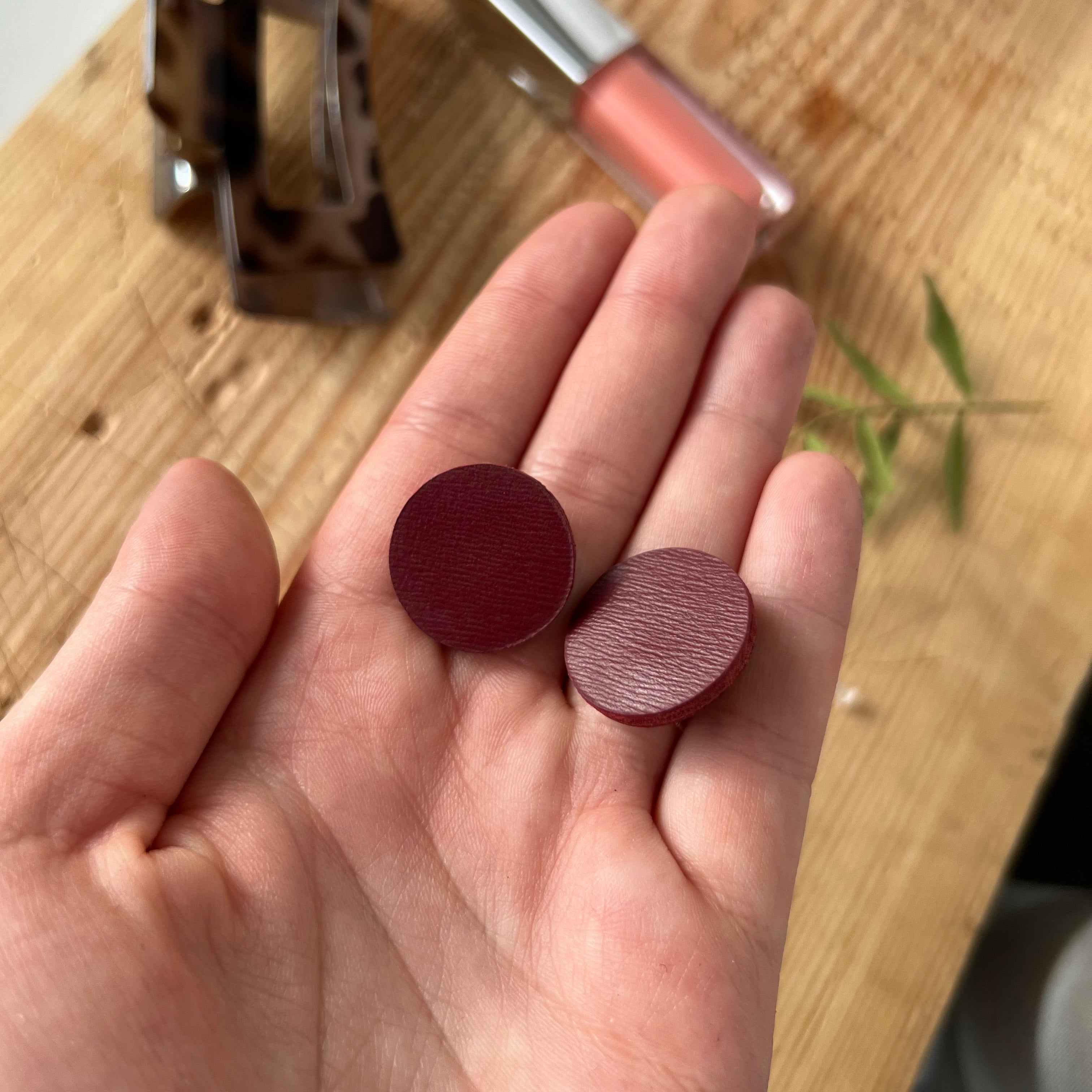 Hand holding two round red objects on a wooden surface