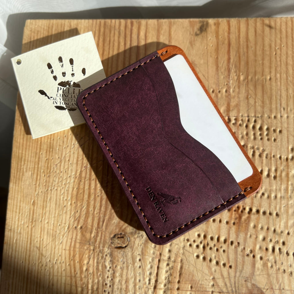 Brown leather wallet on a wooden surface with a white card and handprint design.