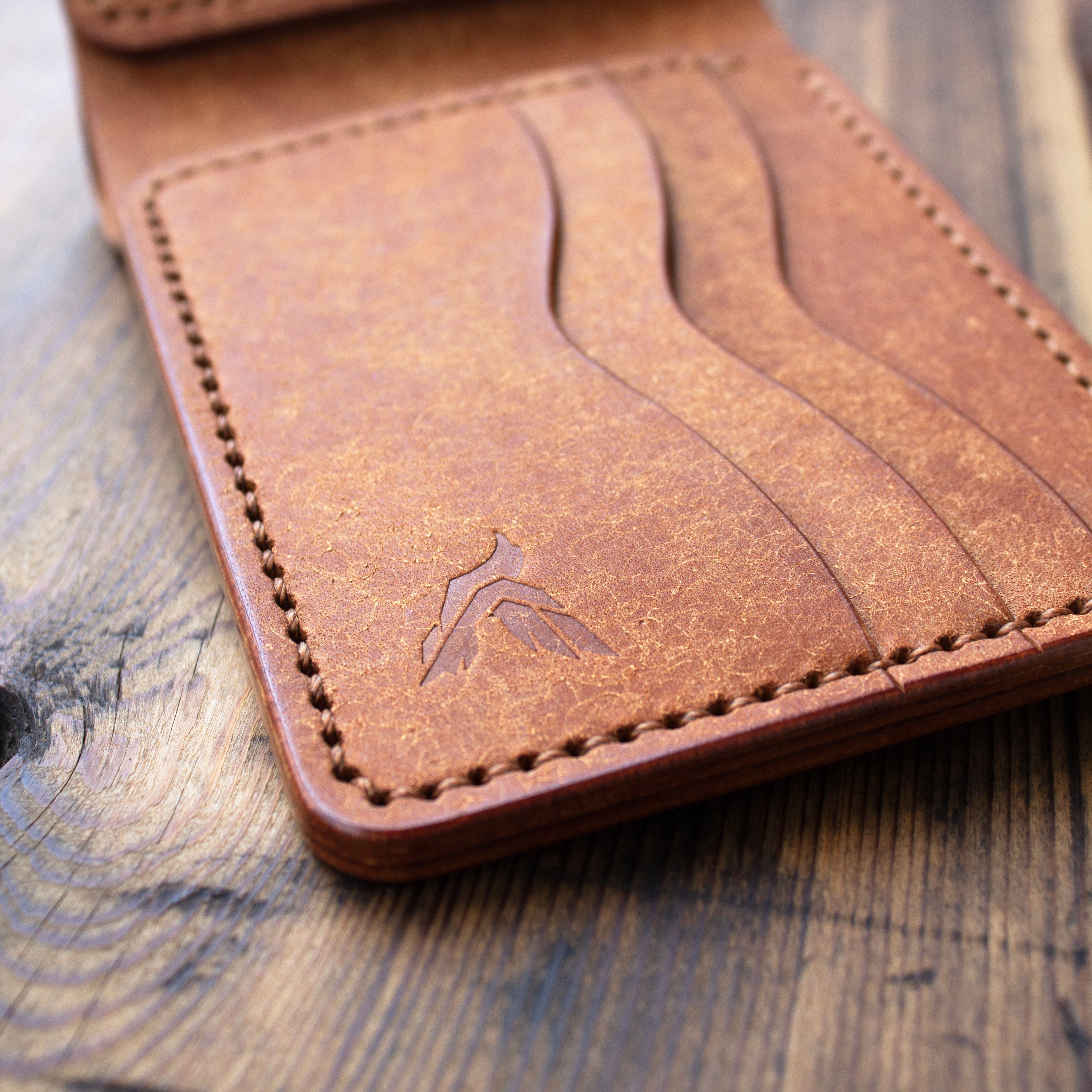 Brown leather wallet with a brand logo on a wooden surface