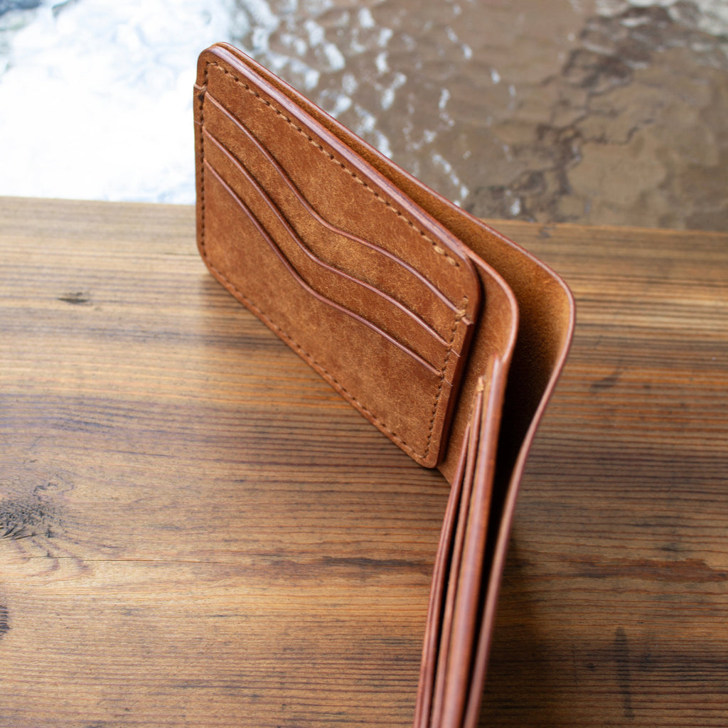 Brown leather wallet on a wooden surface with a blurred background