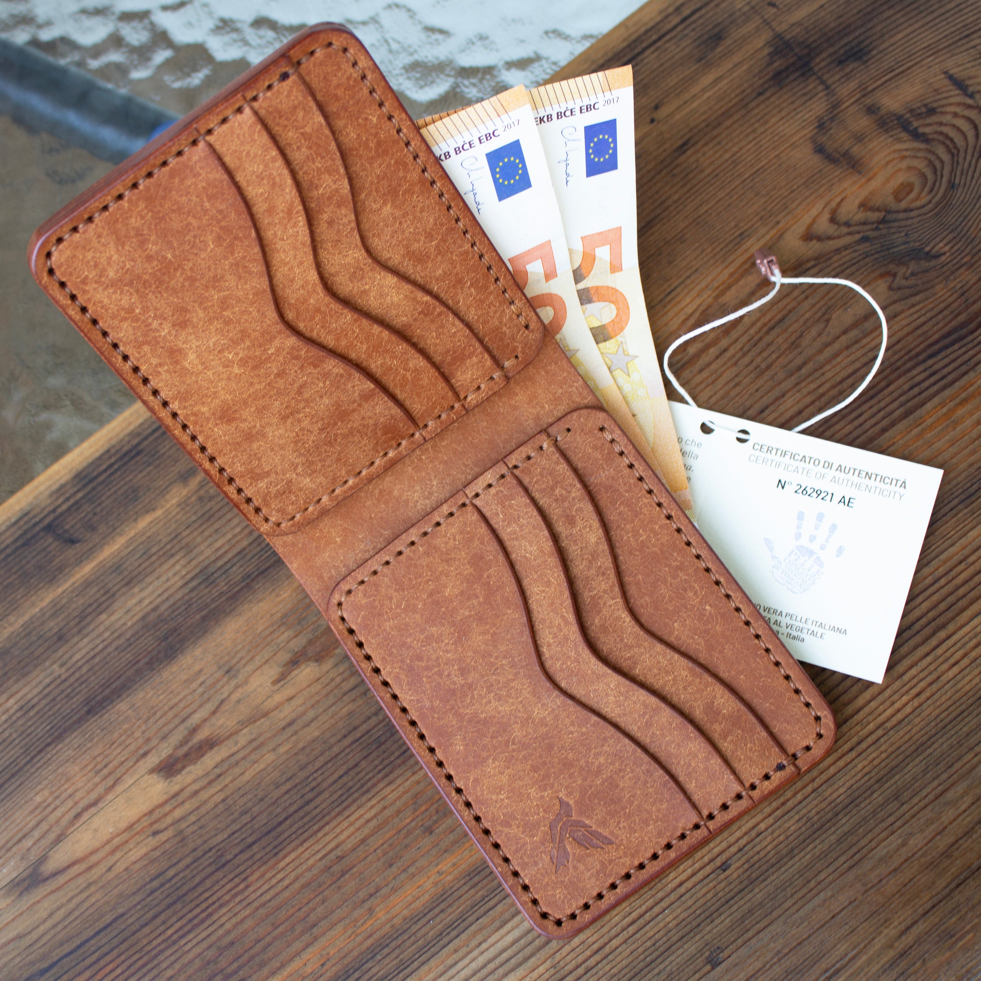 Brown leather wallet with money on a wooden surface