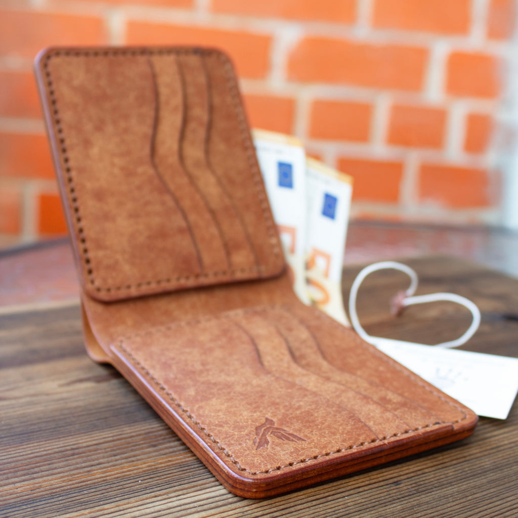 Brown leather wallet on a wooden surface with a brick wall background