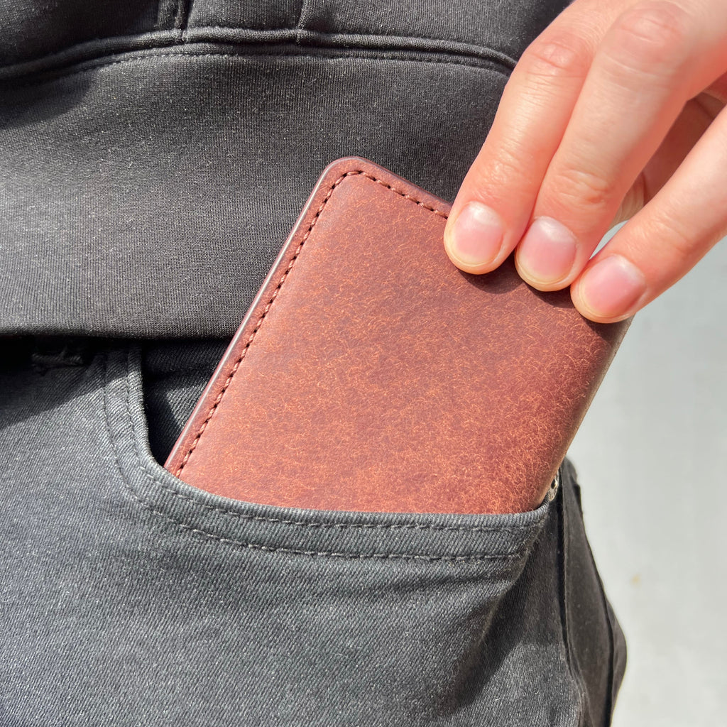 Brown leather wallet being inserted into a gray pocket.
