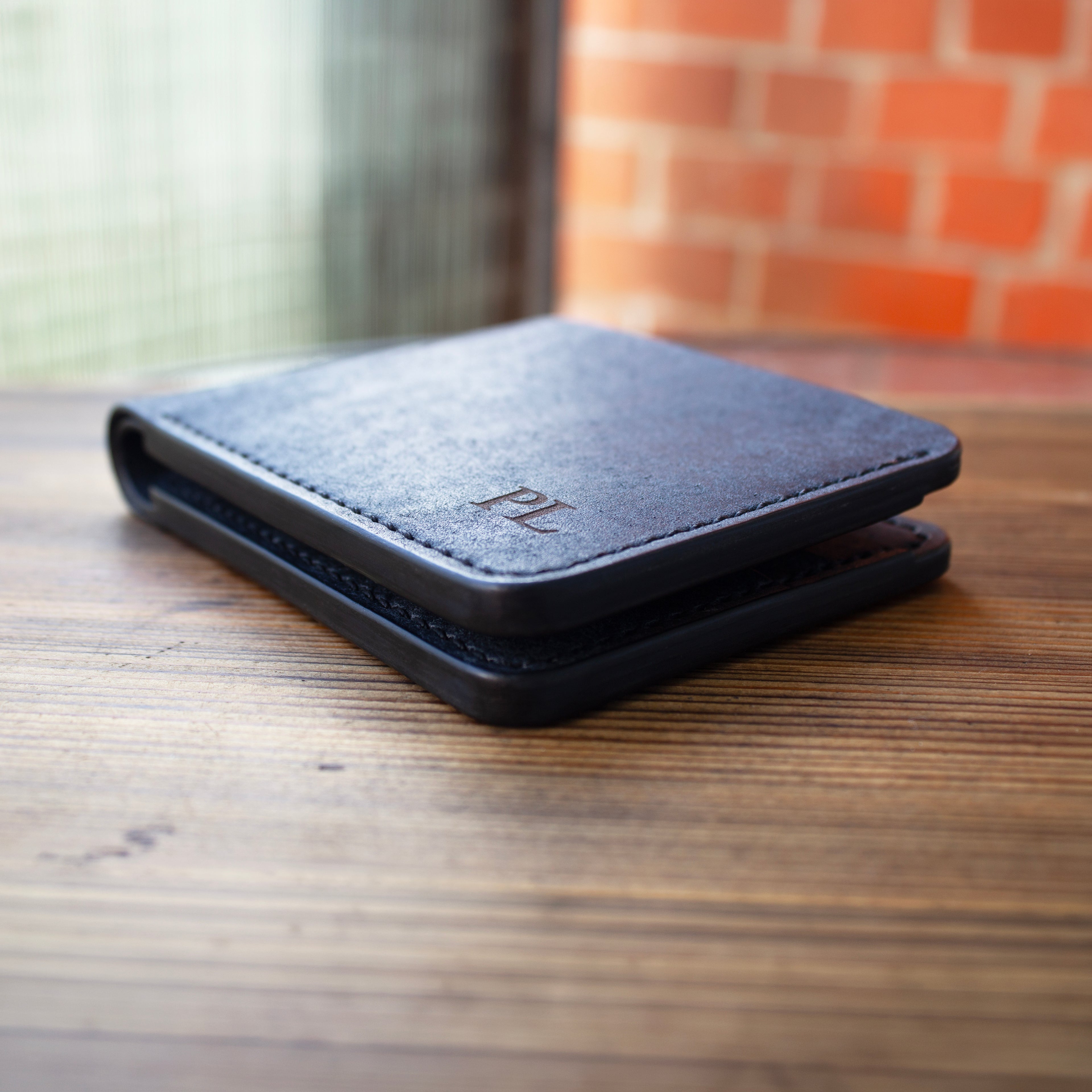 Navy leather wallet with initials on a wooden surface