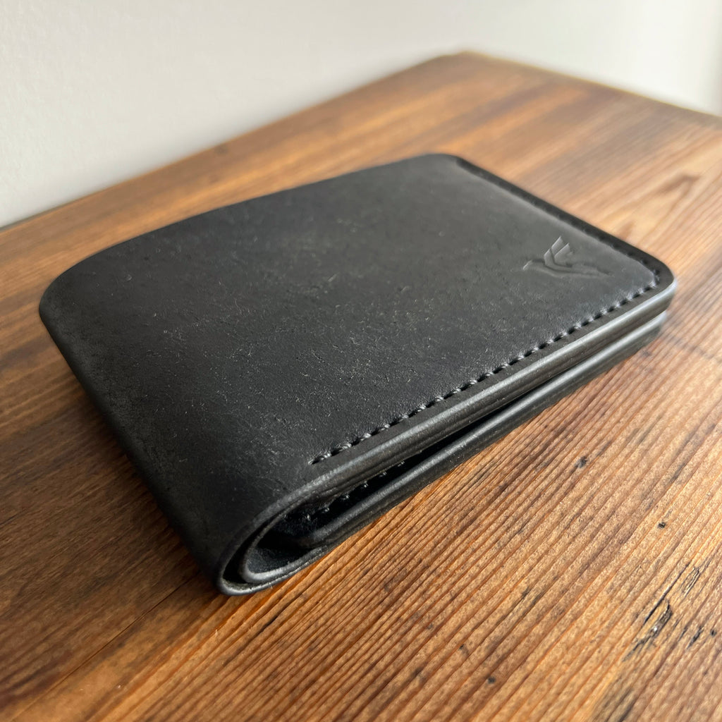 Black leather wallet on a wooden surface