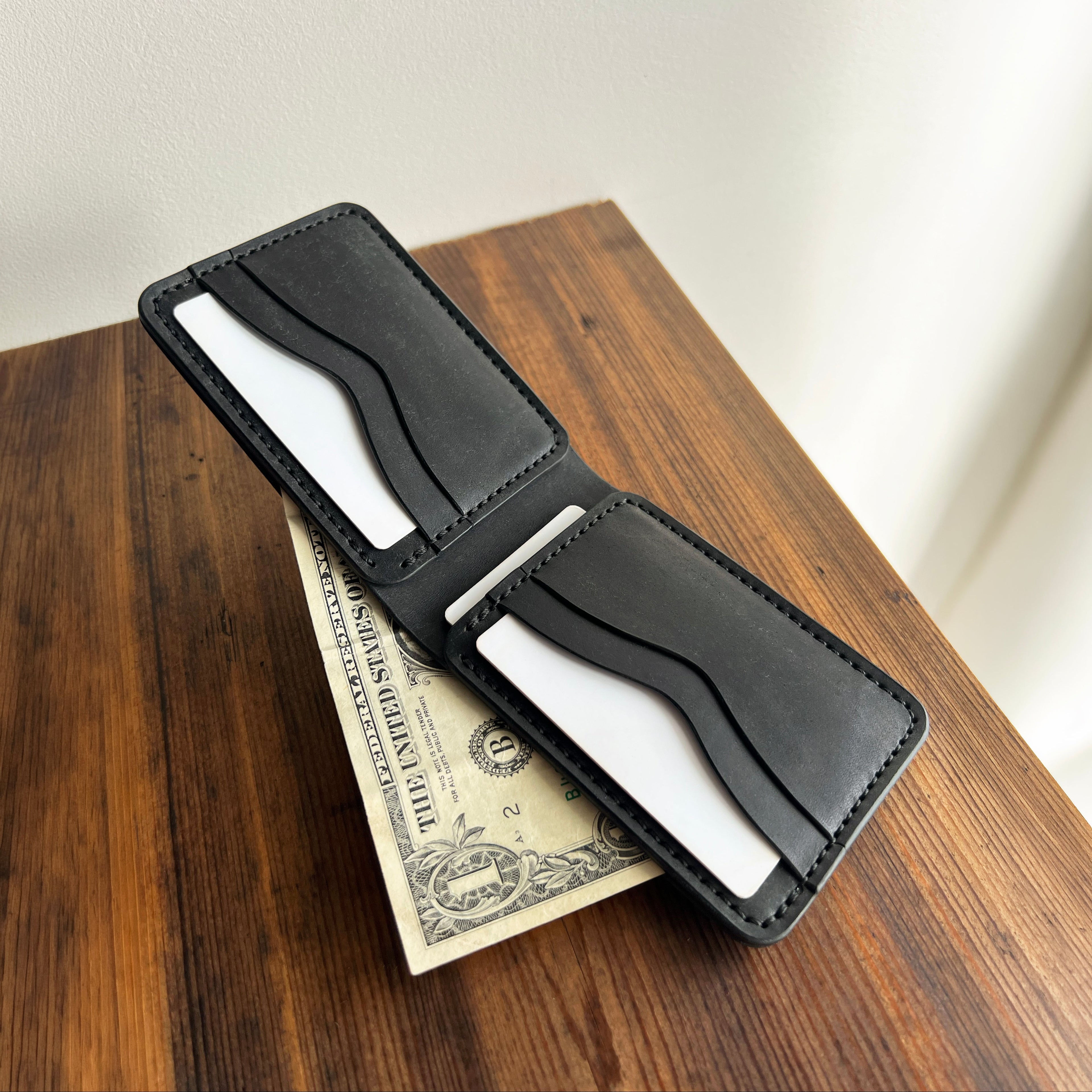 Black leather wallet with money on a wooden surface