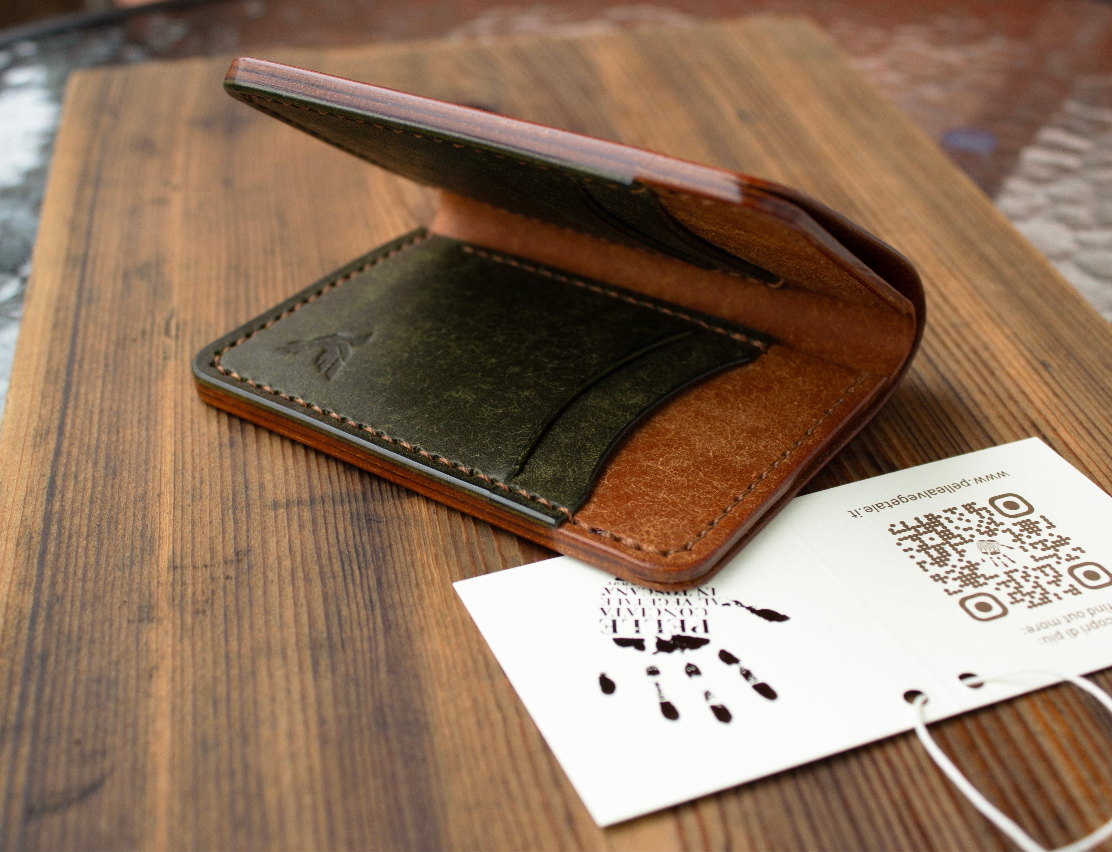 Brown leather wallet on a wooden surface with a white card featuring a QR code.