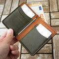Hand holding a leather wallet with money on a wooden floor background
