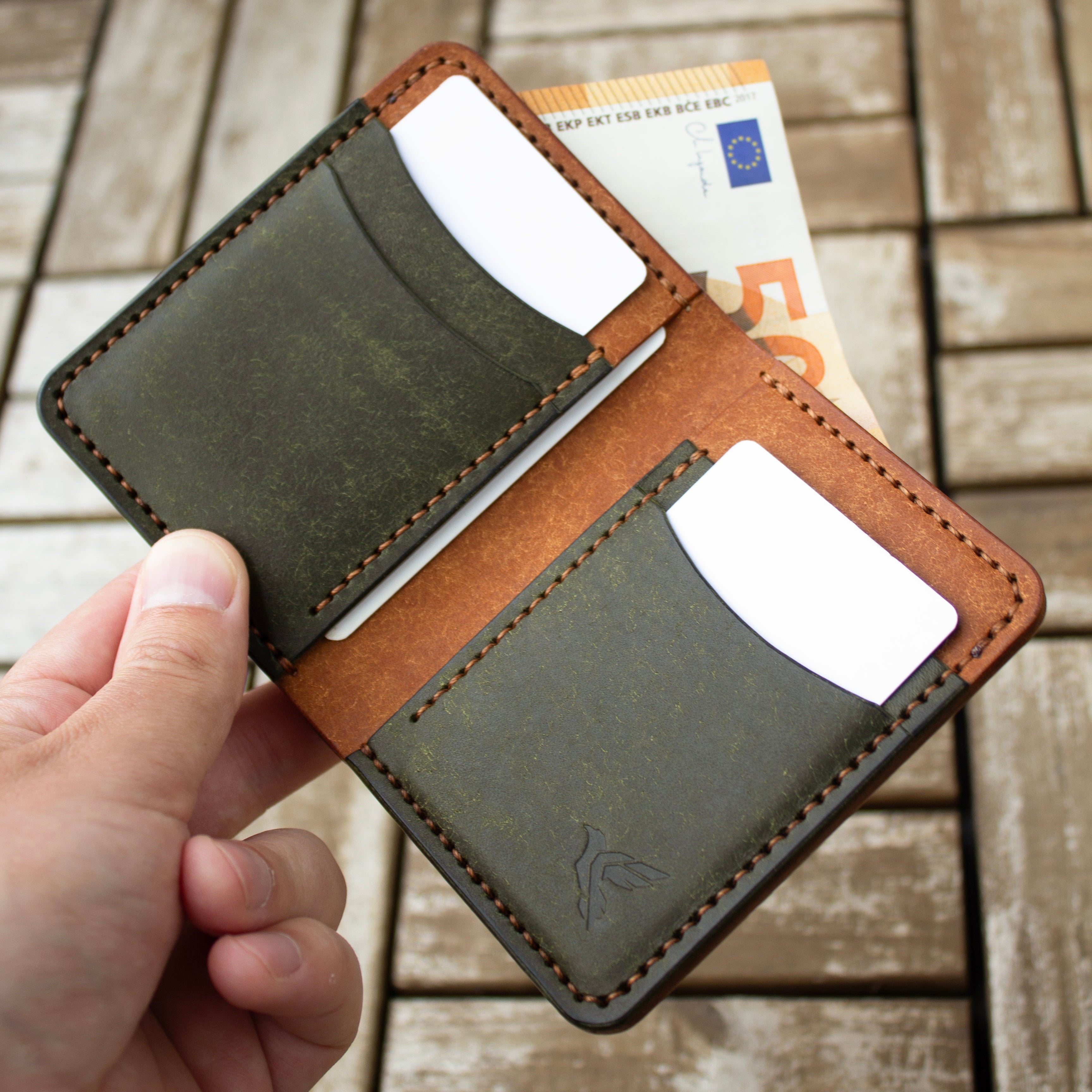 Hand holding a leather wallet with money on a wooden floor background