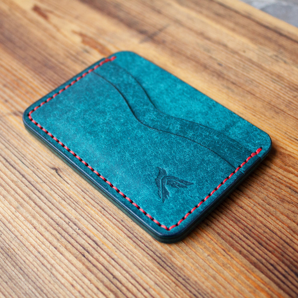 Blue leather cardholder with red stitching on a wooden surface