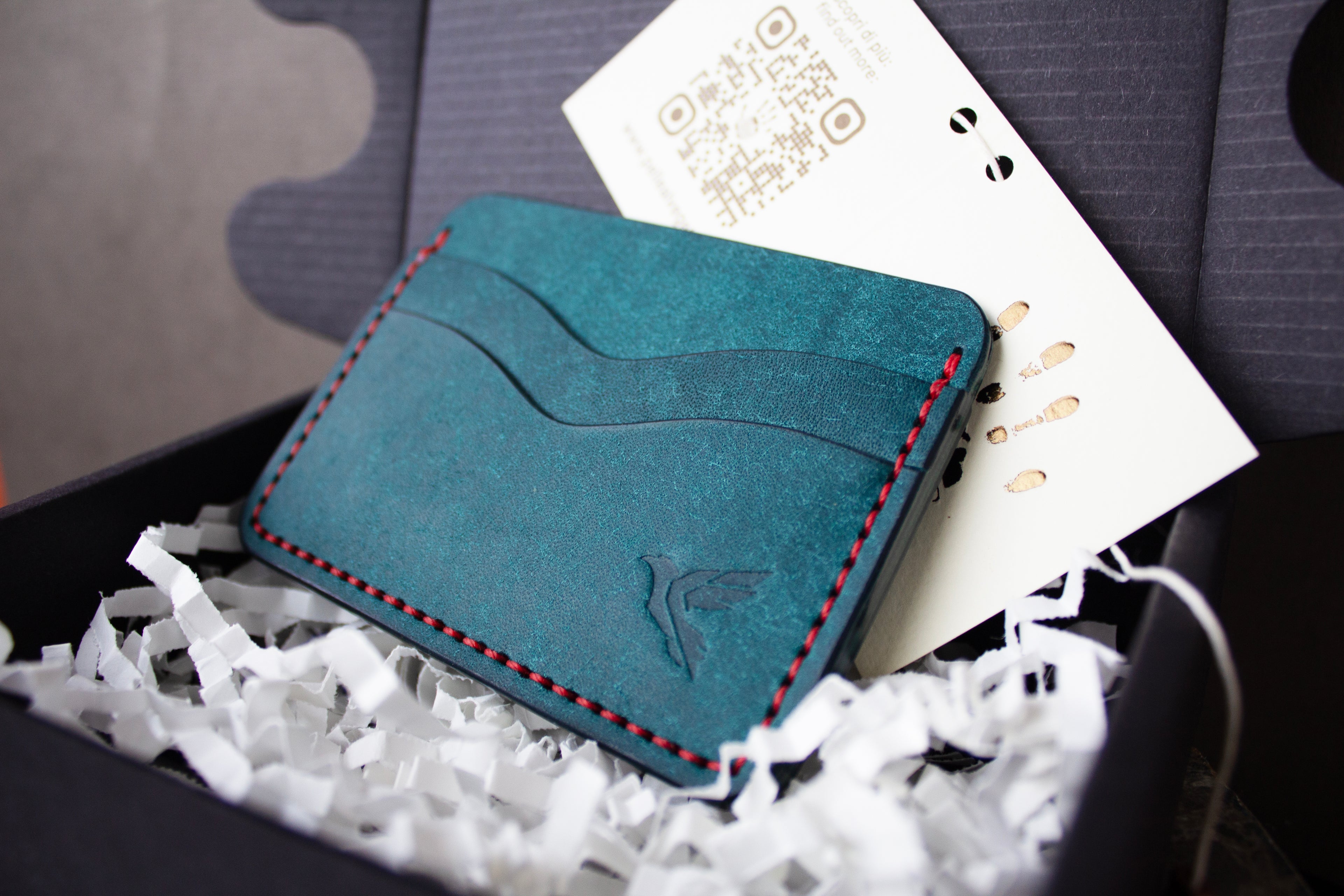 Blue leather cardholder with red stitching on a white crinkled paper background