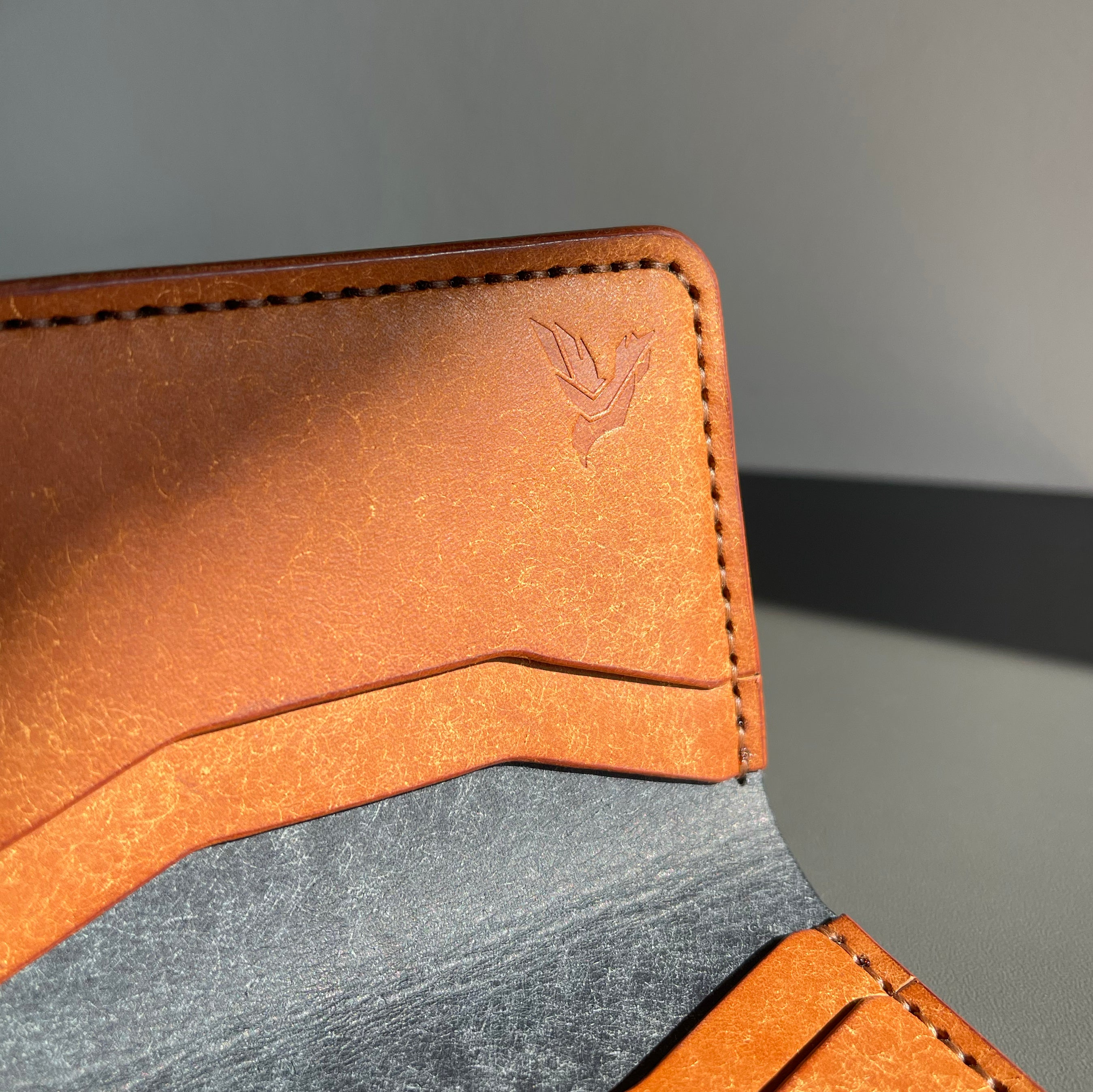 Close-up of a brown leather wallet with a visible brand logo on a gray background