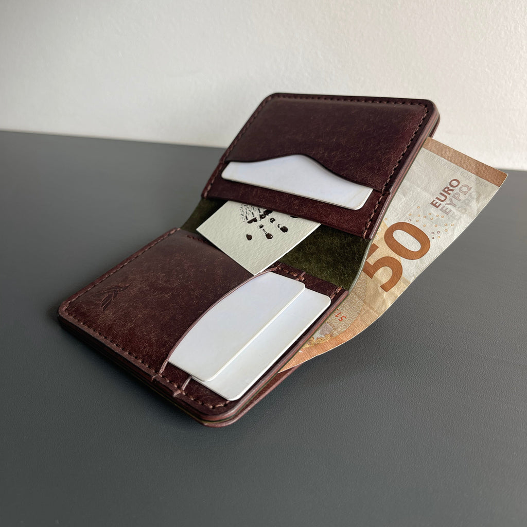 Brown leather wallet with money and cards on a gray surface