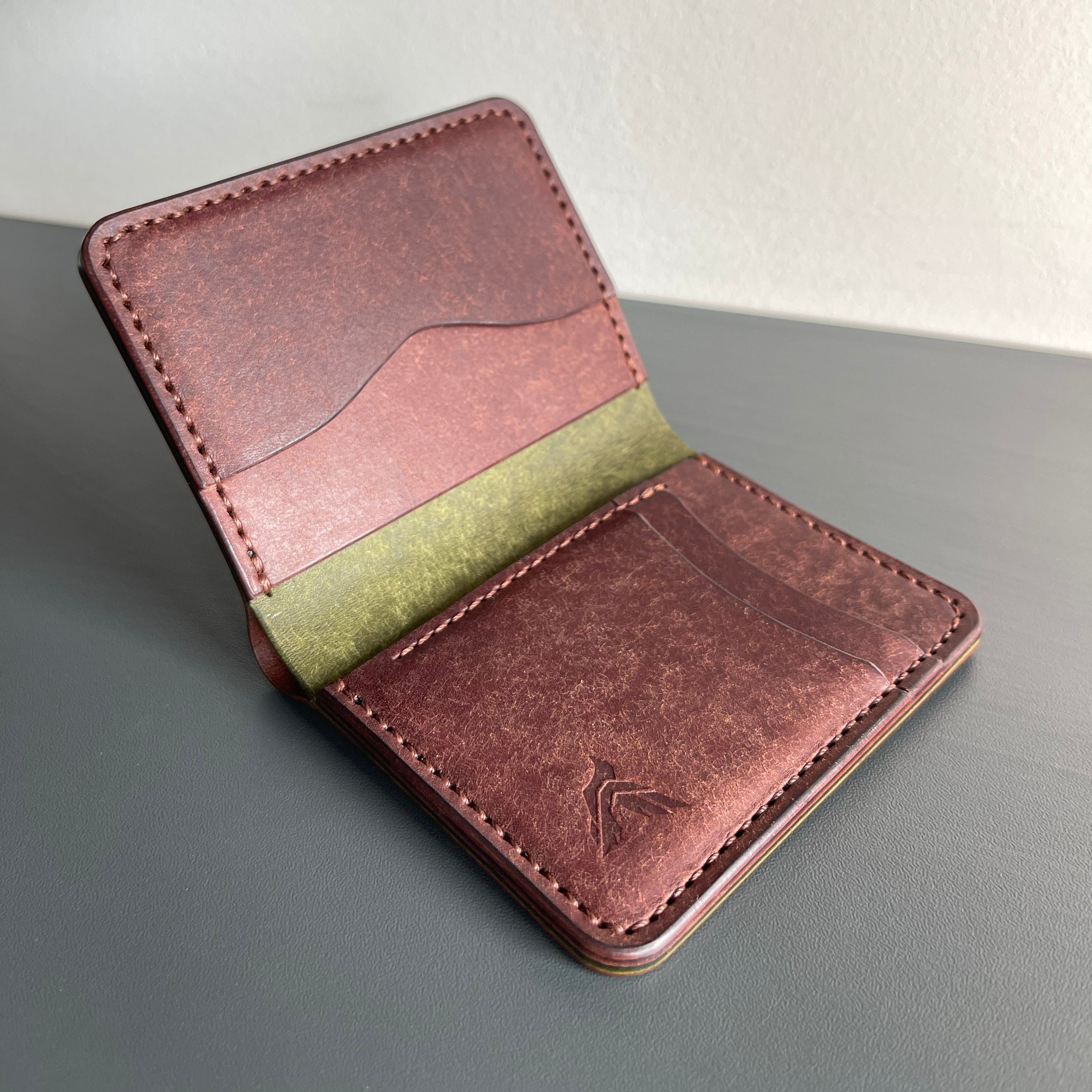Brown leather wallet with green interior on a gray surface