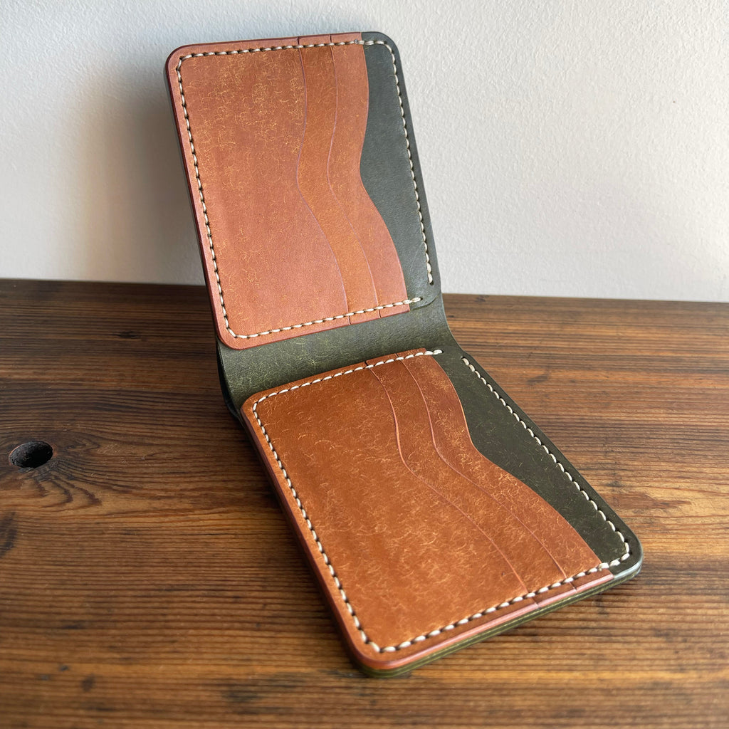 Brown leather wallet on a wooden surface with a white background