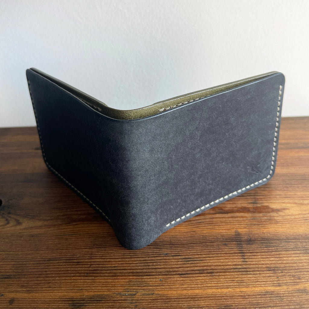 Black leather wallet on a wooden surface with a white background