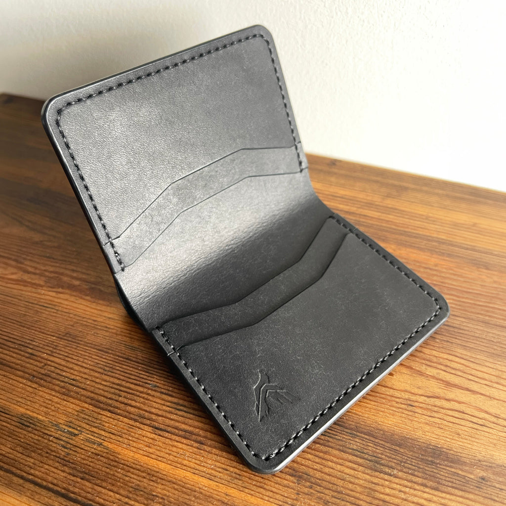 Gray leather wallet on a wooden surface with a white background
