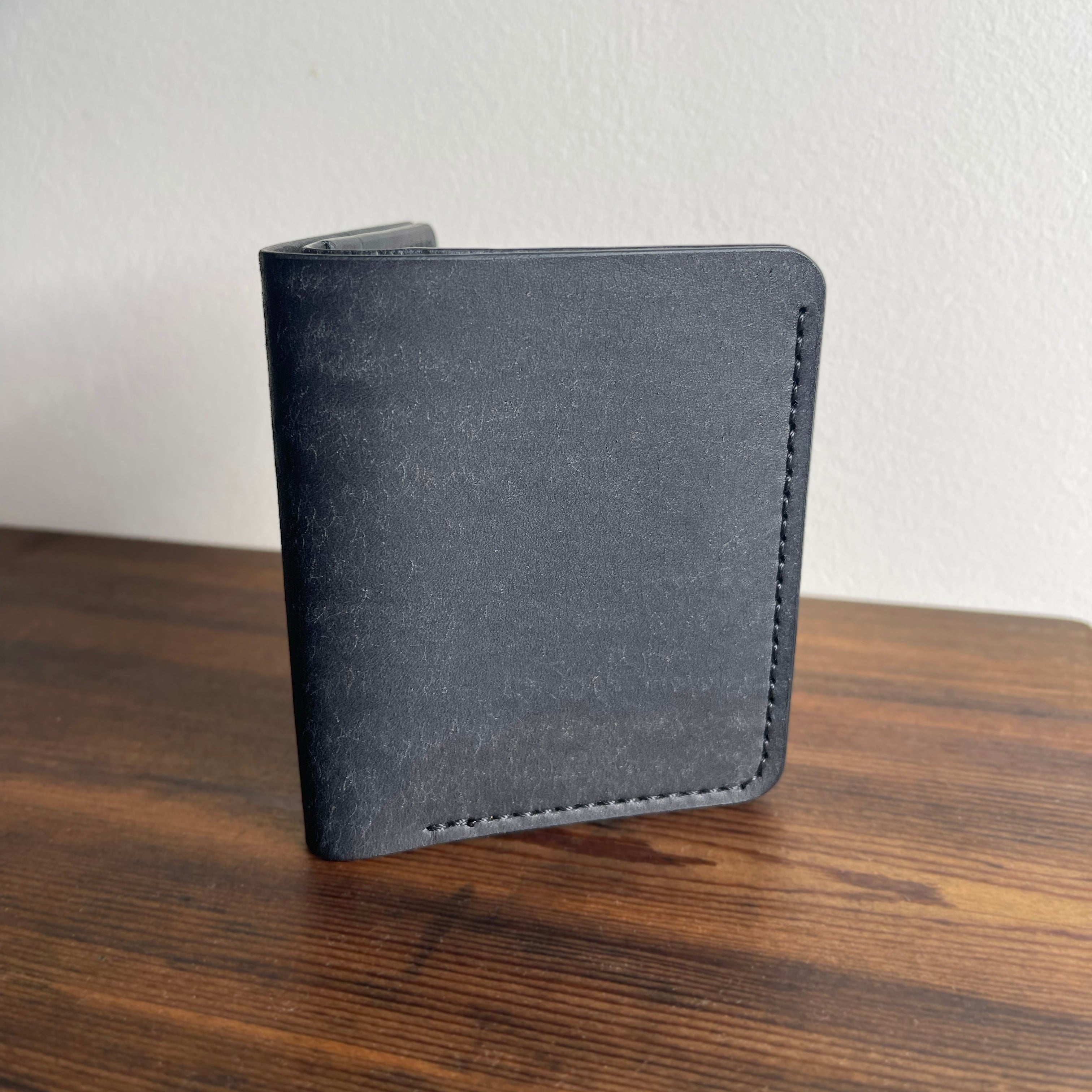 Gray wallet on a wooden surface with a light gray background