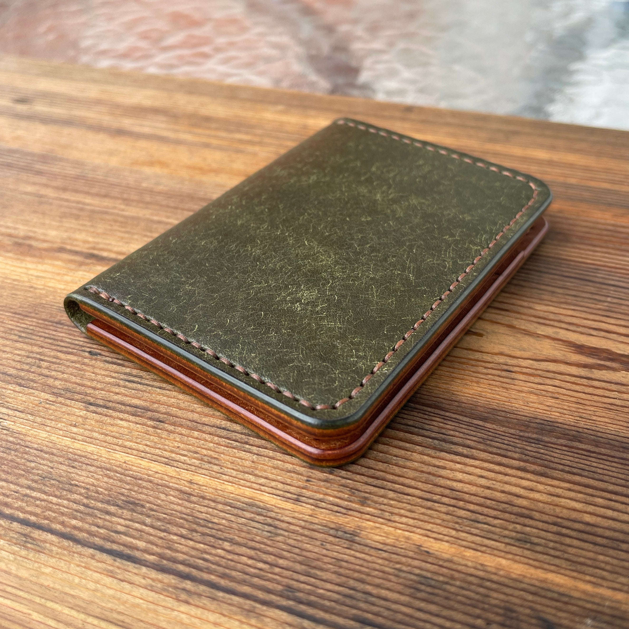 Green leather wallet on a wooden surface