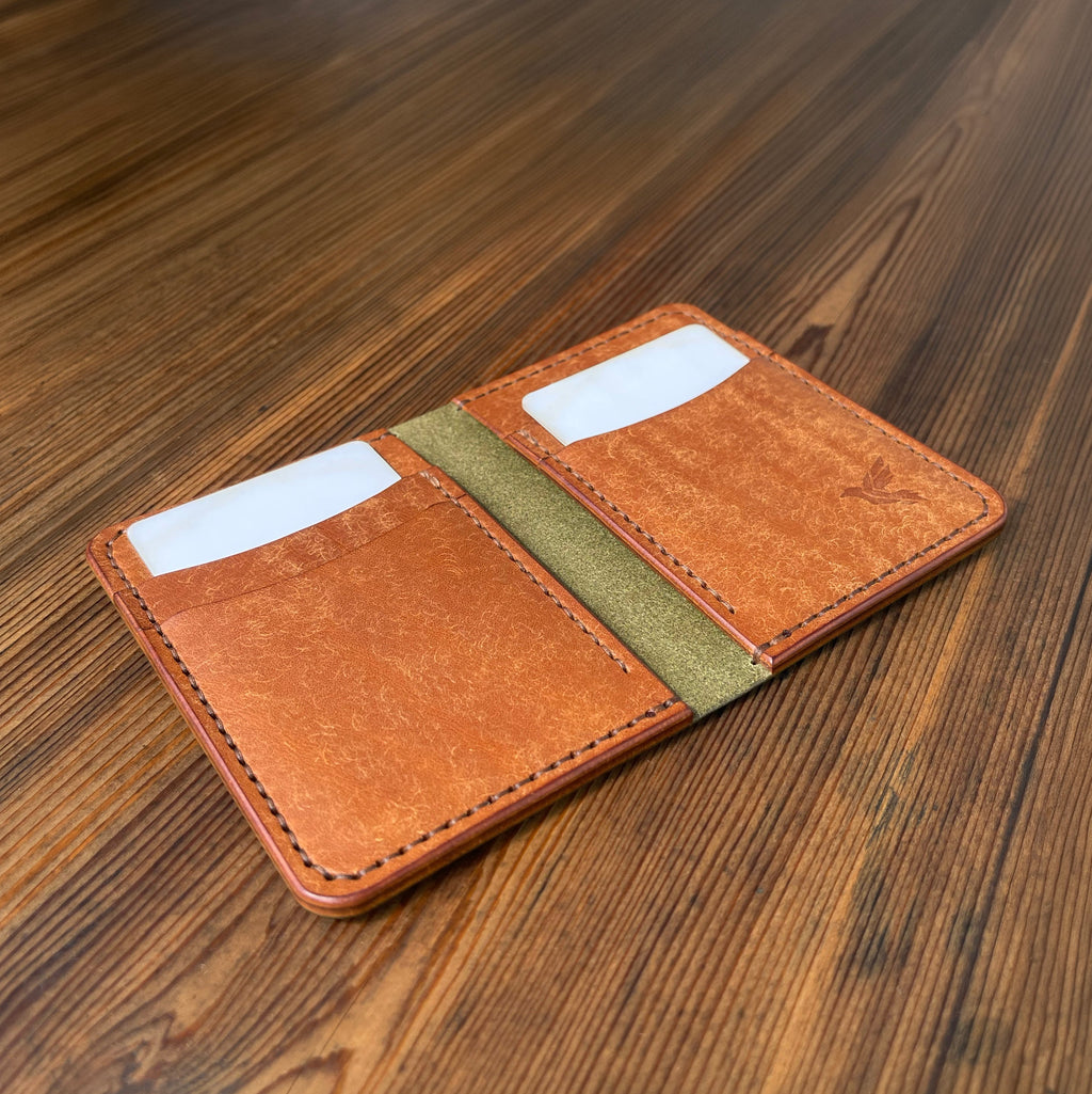 Brown leather wallet with a green stripe on a wooden surface