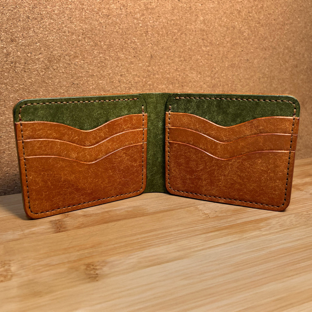 Two-tone leather wallet with green and brown sections on a wooden surface.