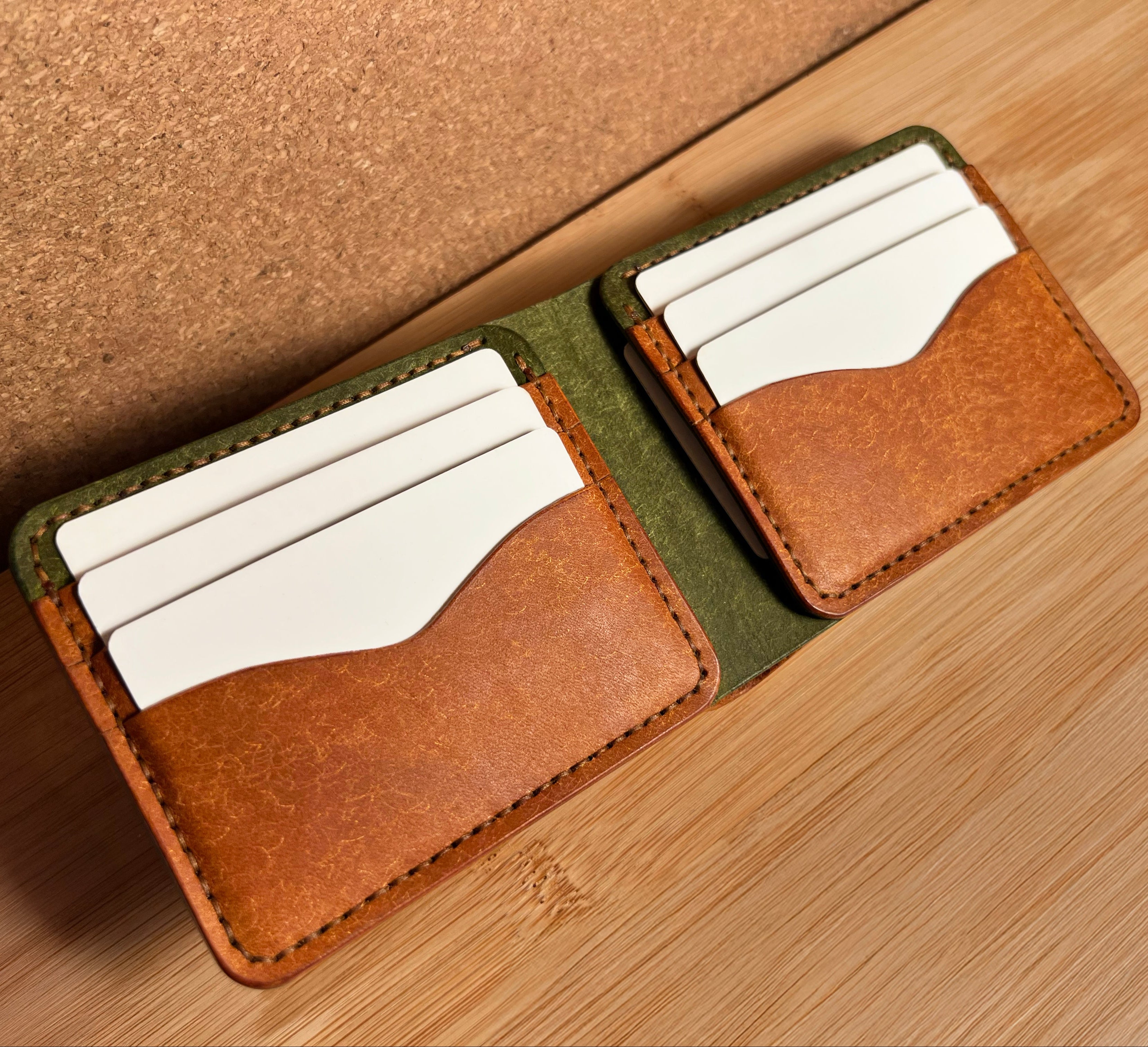 Two leather card holders with white cards on a wooden surface