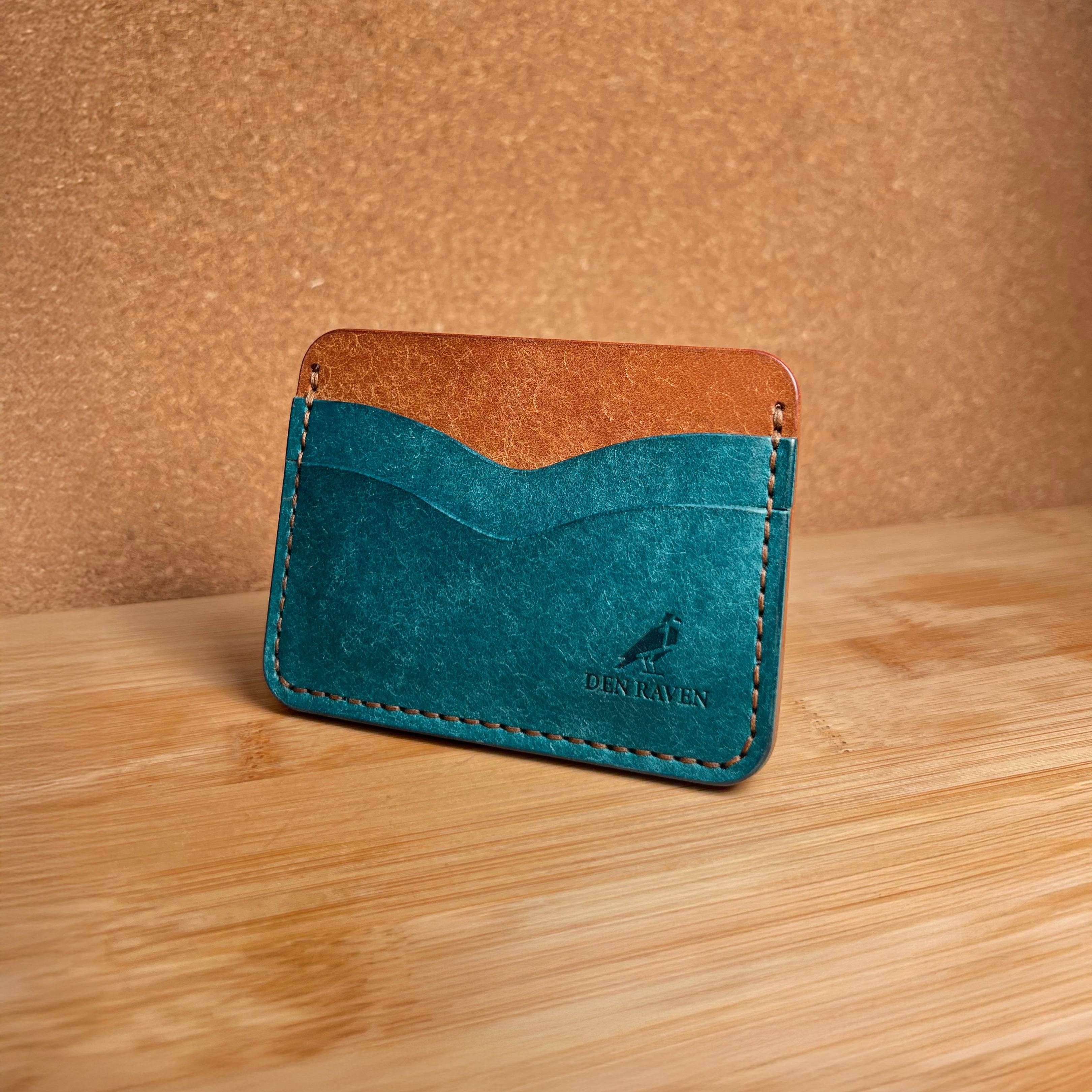 Two-tone leather wallet with teal front and brown back on a wooden surface