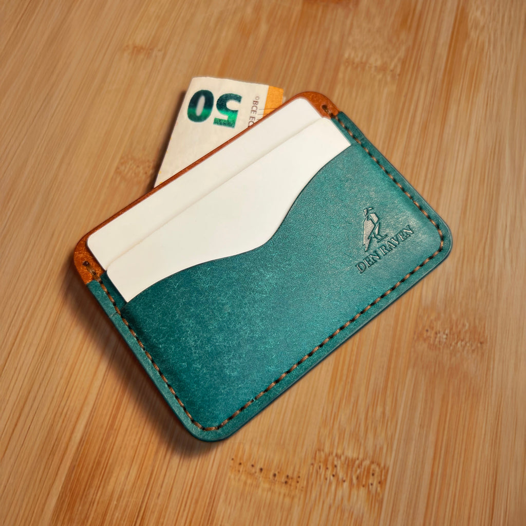 Teal leather cardholder with a card and money on a wooden surface