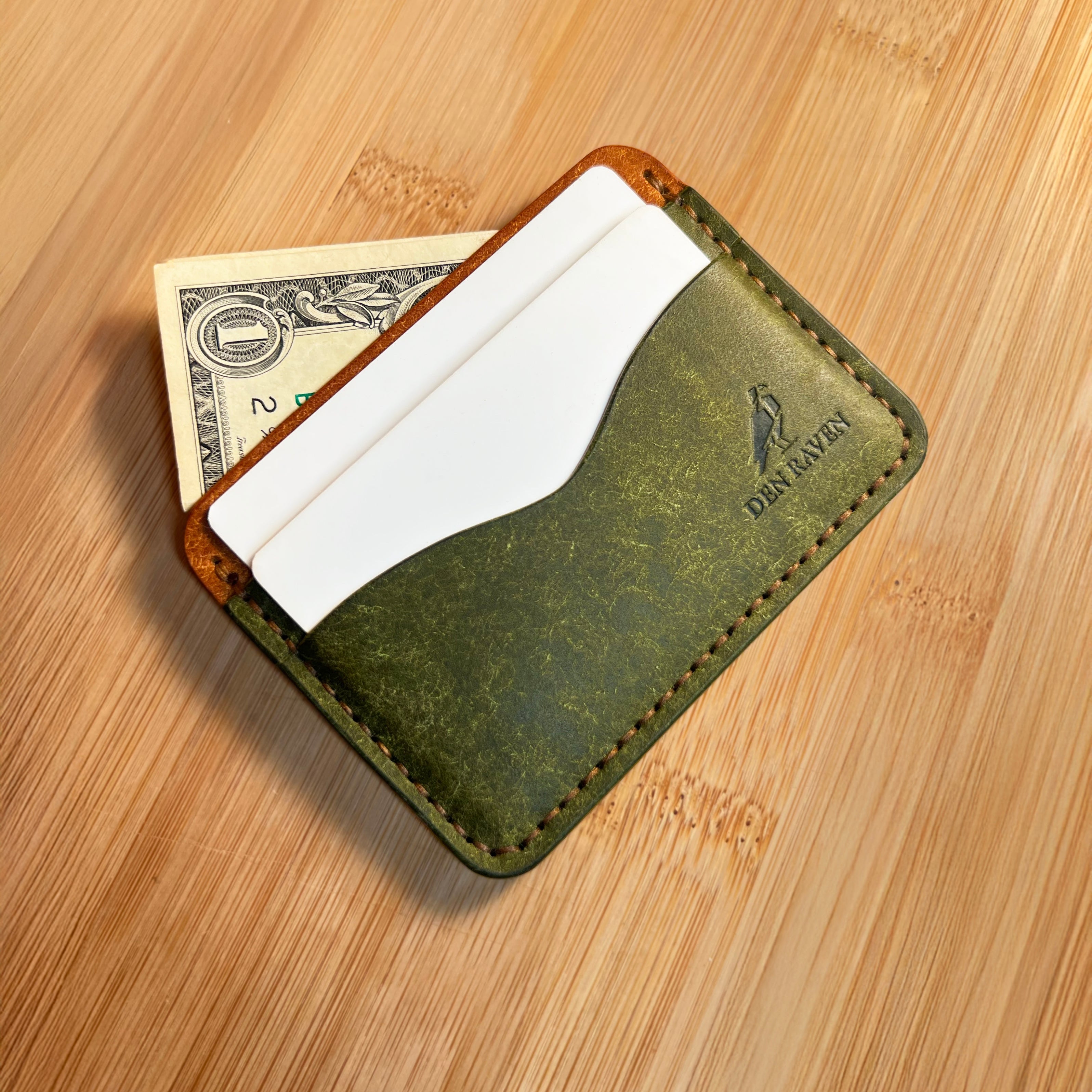 Green leather wallet with money and cards on a wooden surface