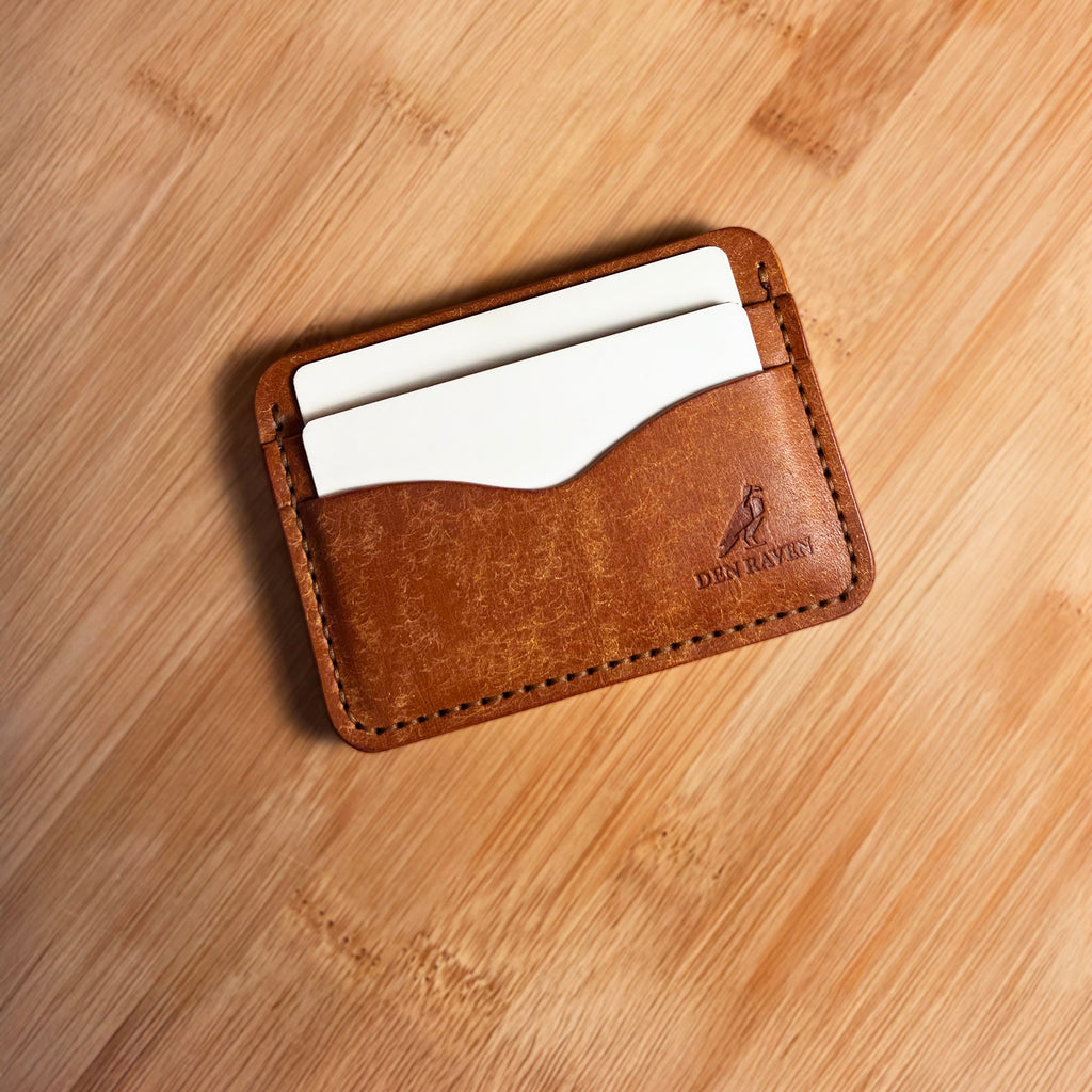 Brown leather cardholder with white cards on a wooden surface