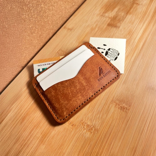 Brown leather cardholder with cards on a wooden surface