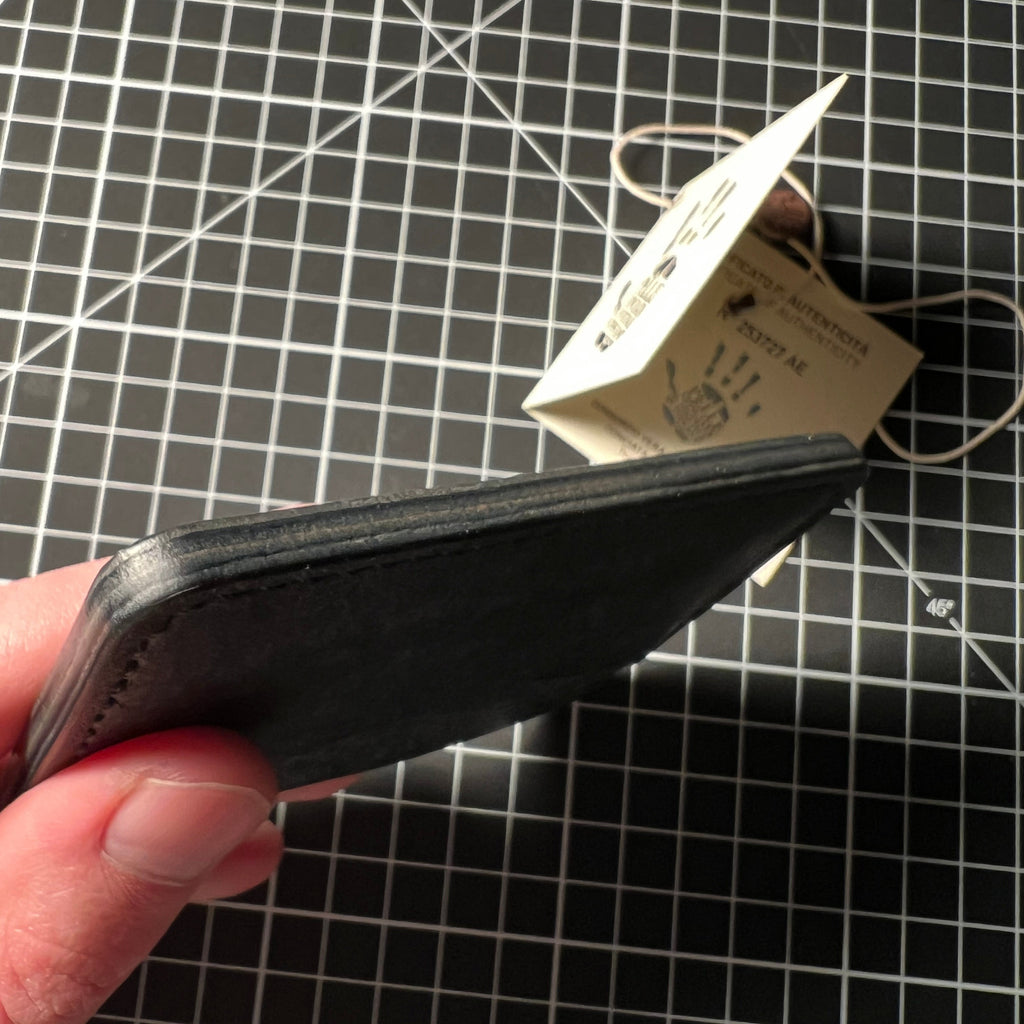 Black leather wallet with a tag held over a grid background