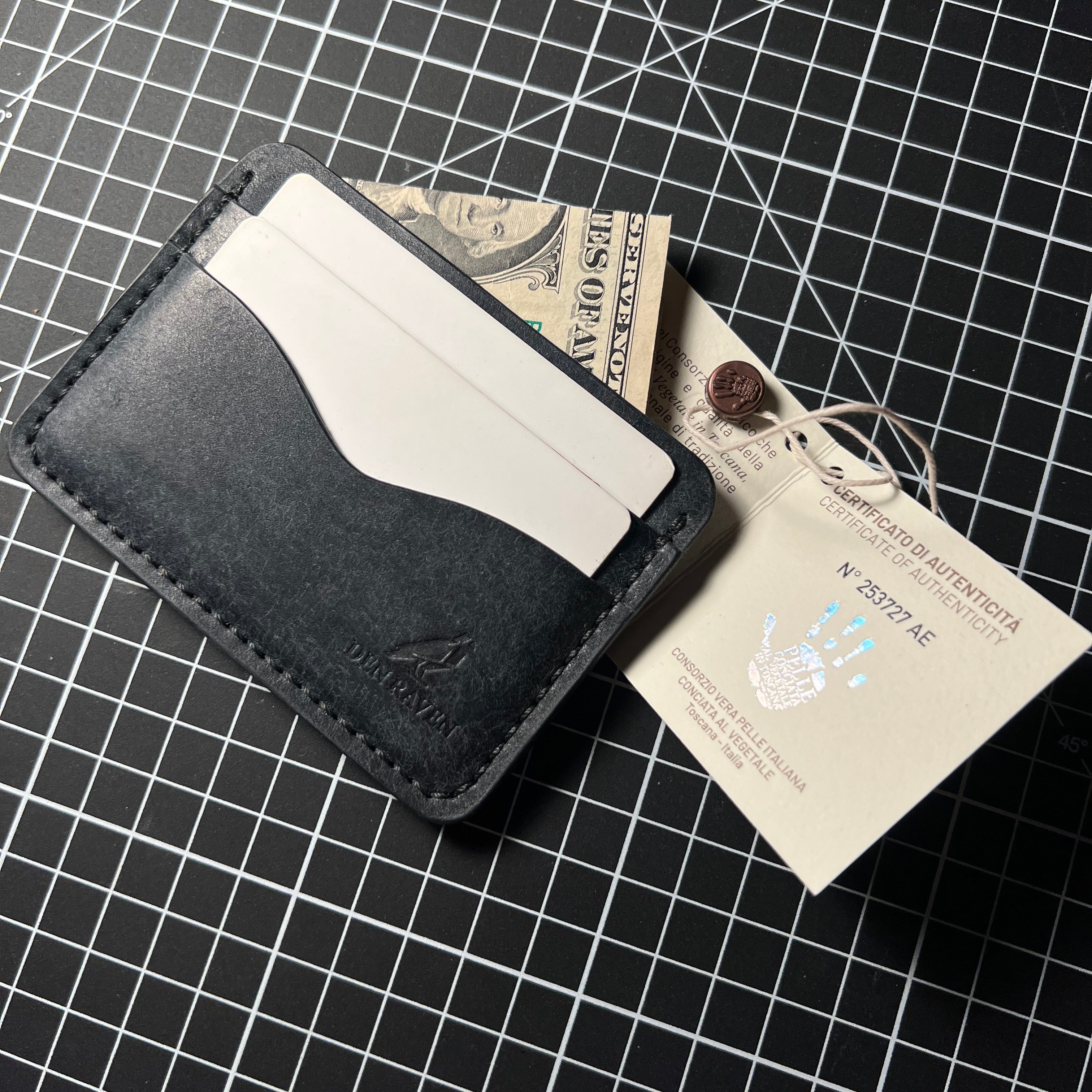 Black leather wallet with a card and money on a grid background