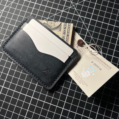 Black leather wallet with a card and money on a grid background