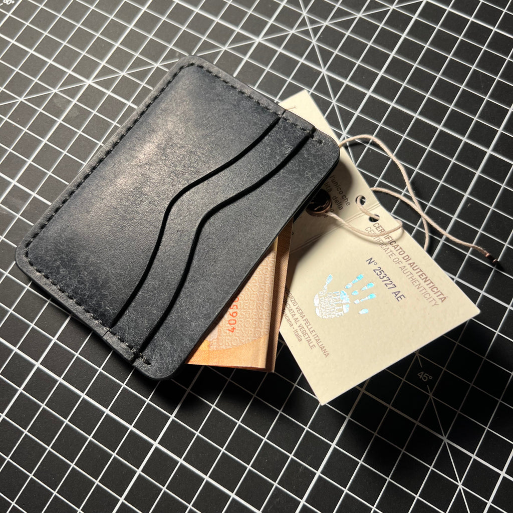 Black leather wallet with a card and paper on a grid background
