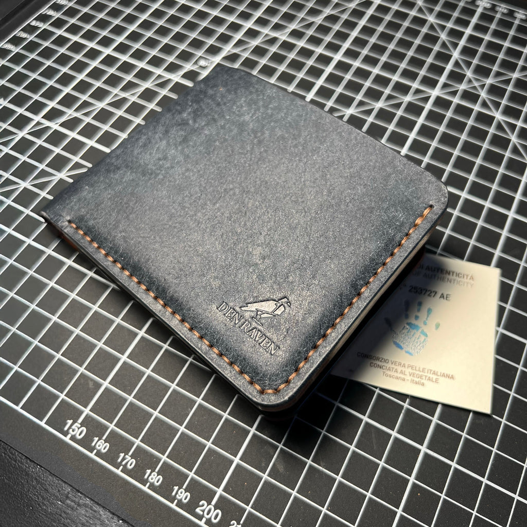 Gray leather wallet on a grid surface with a card inside
