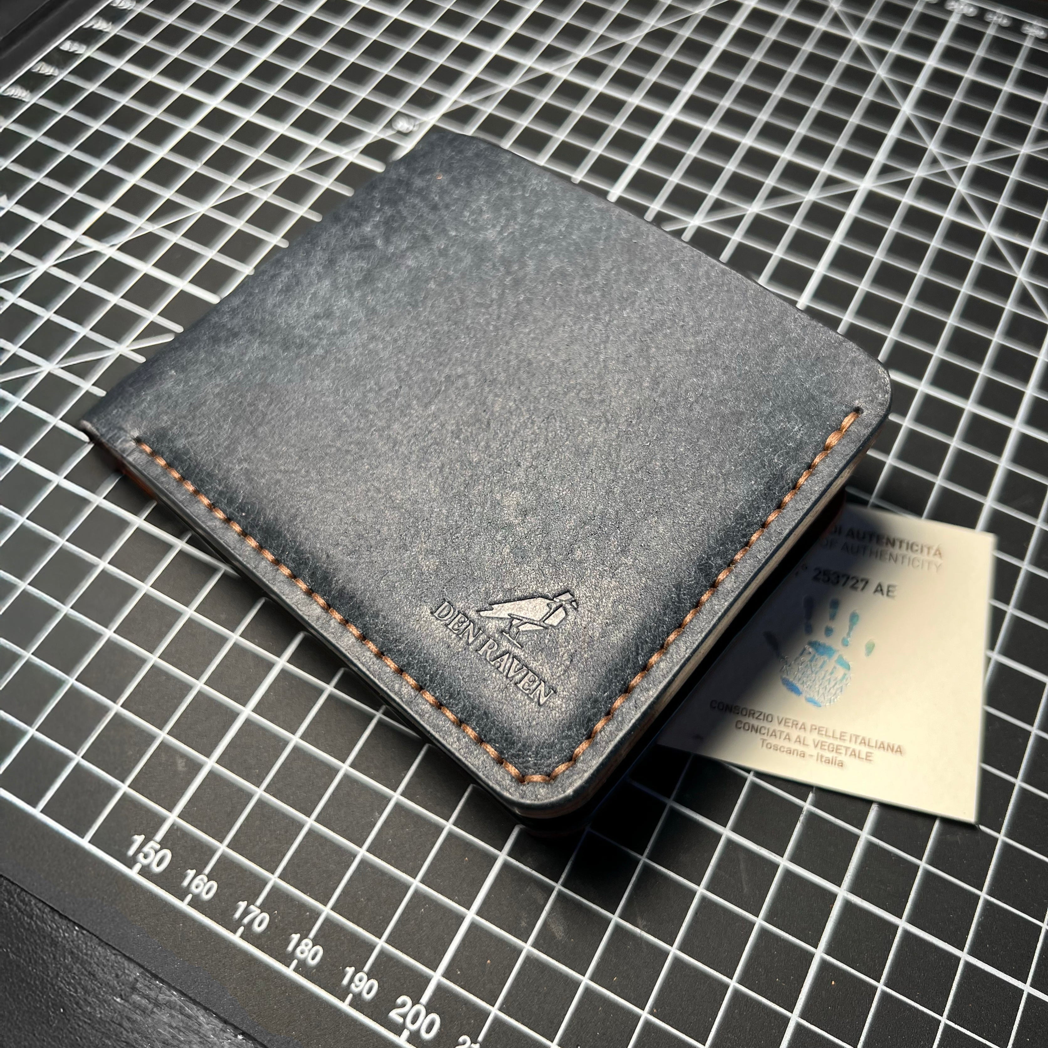 Gray leather wallet on a grid surface with a card inside