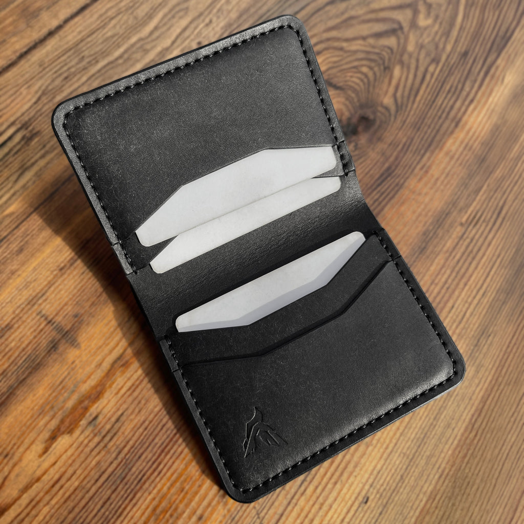 Black leather wallet with card slots on a wooden surface