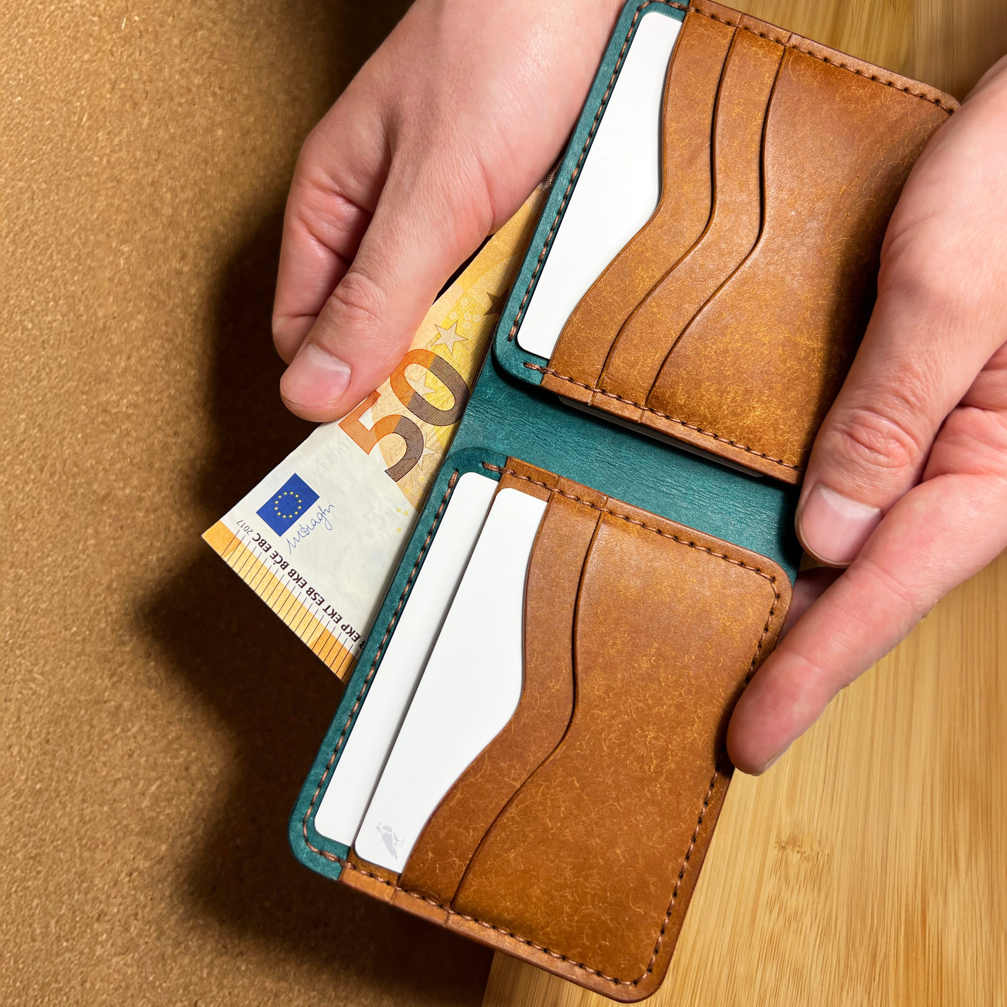 Brown leather wallet with cards and a 50 euro bill on a wooden surface