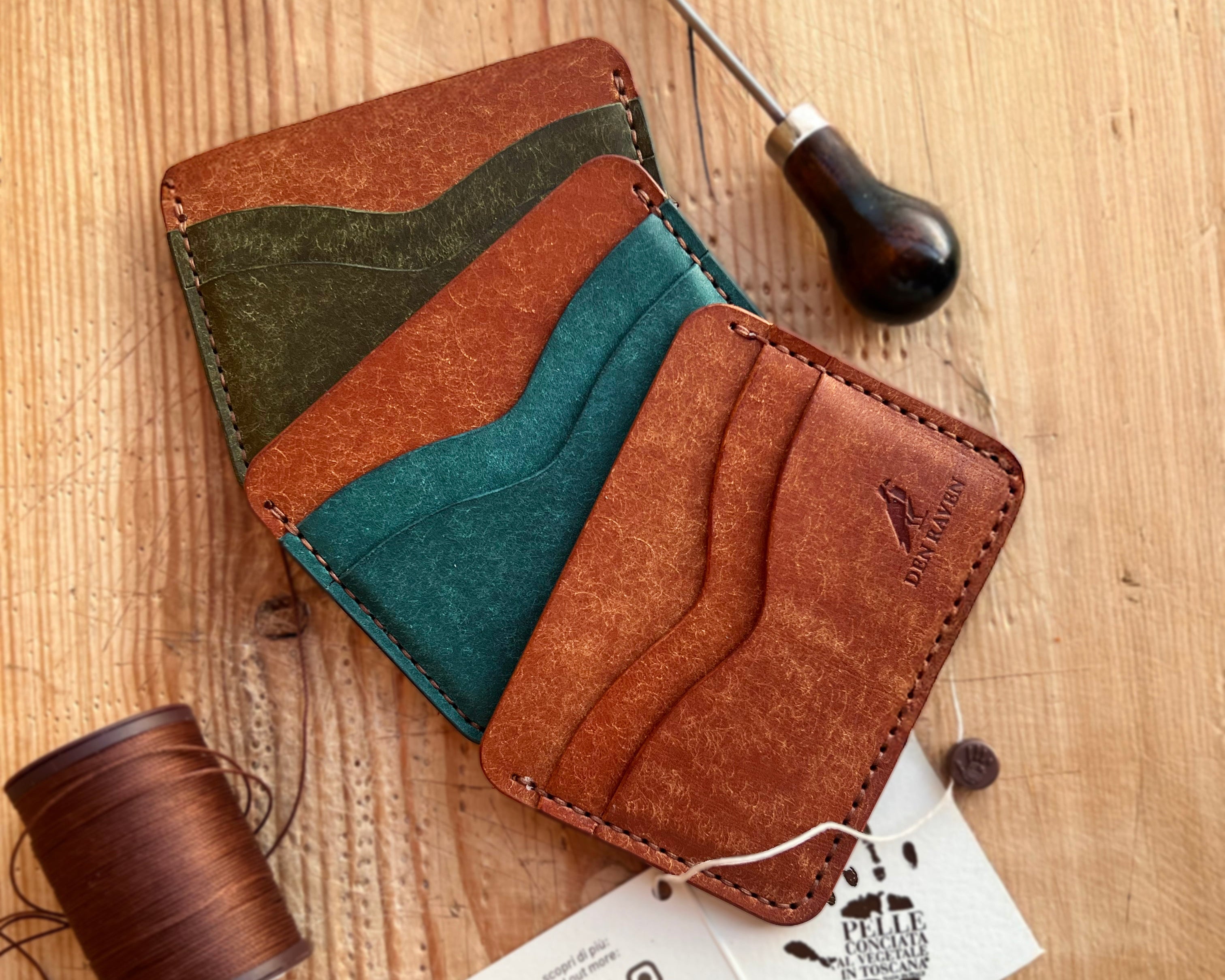 Brown leather wallet with green and blue accents on a wooden surface with tools.