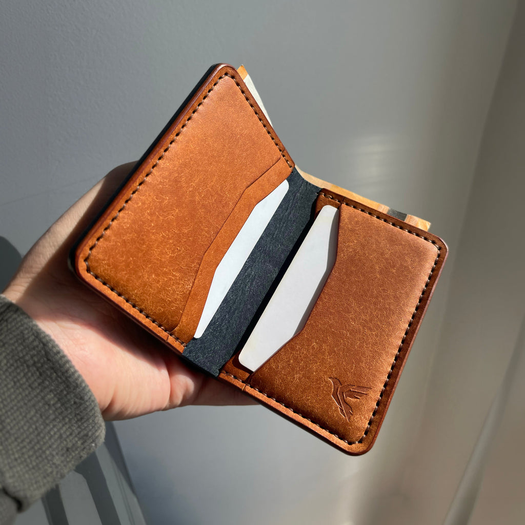 Brown leather wallet with card slots held in a hand against a neutral background